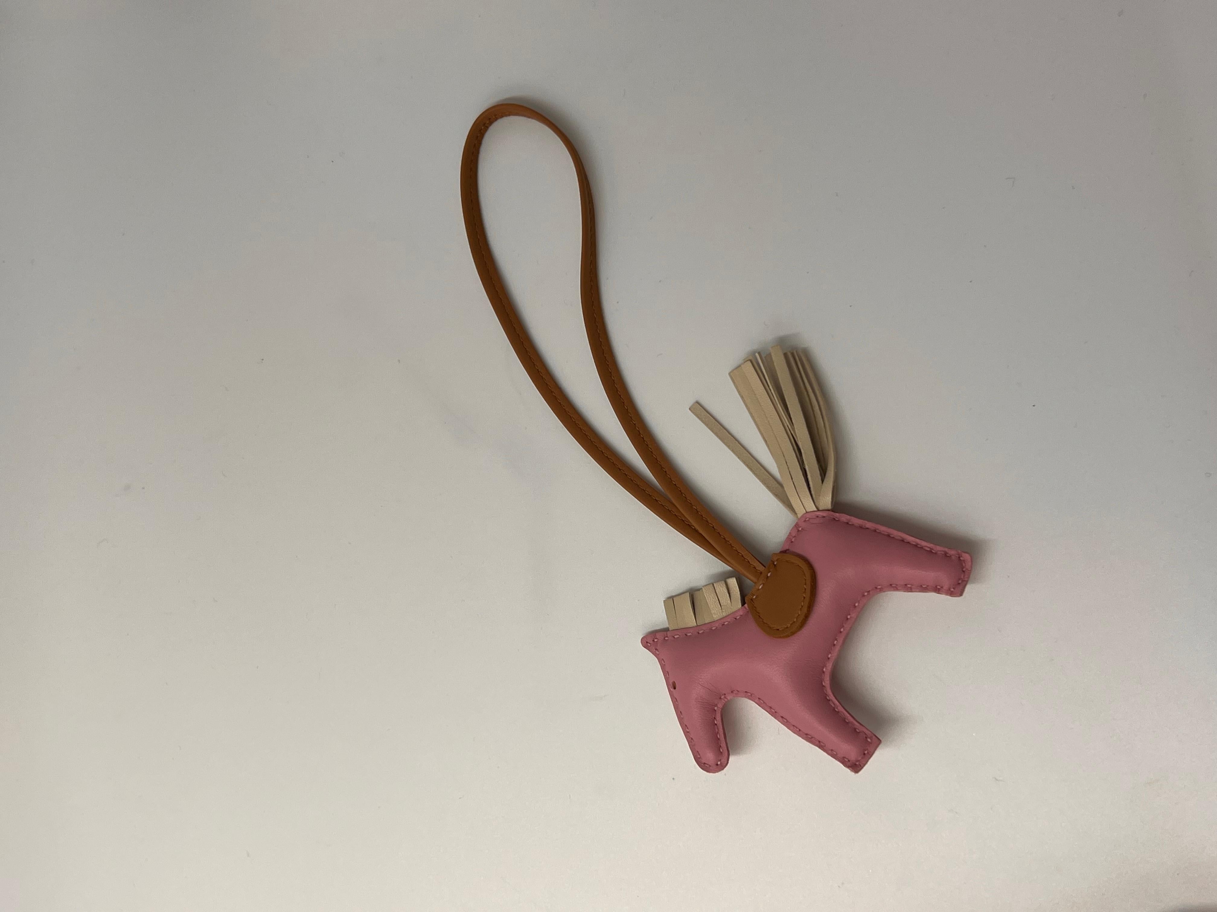 Hermès Mauve Sylvestre/Chai/Craie Grigri Horse Rodeo Bag Charm PM. 
This Grigri Rodeo bag charm is in Mauve Sylvestre Milo lambskin leather and accented with a Craie mane and tail and a Chai saddle and holder. Condition is brand new & comes in a