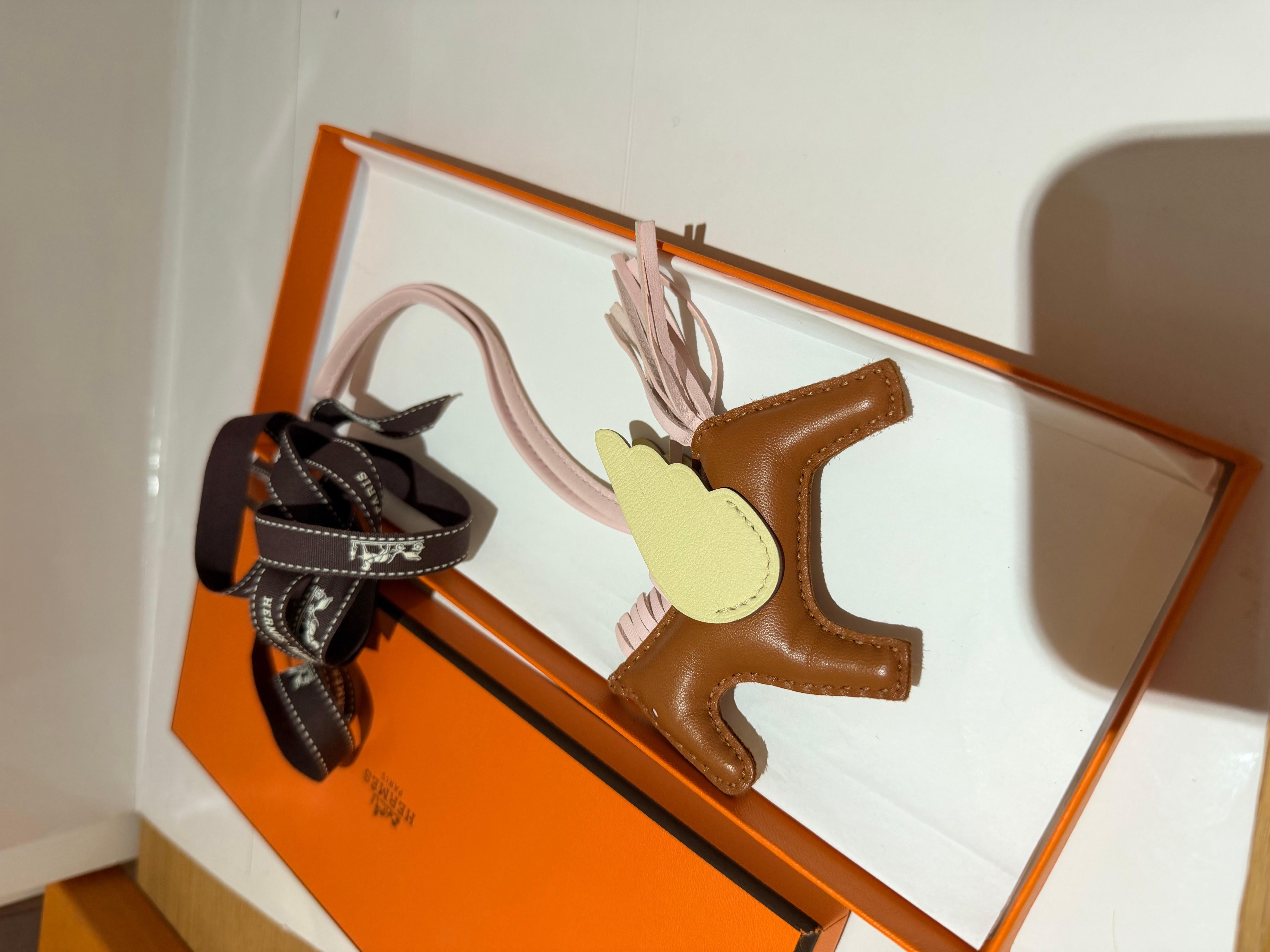 The Hermes Rodeo Pegasus PM Bag Charm is crafted from Agneau Milo and Swift leather, featuring a design that combines elegance with playful charm,  suitable for enhancing your handbag's aesthetic.

Color combination is Gold / Rose Darling / Jaune