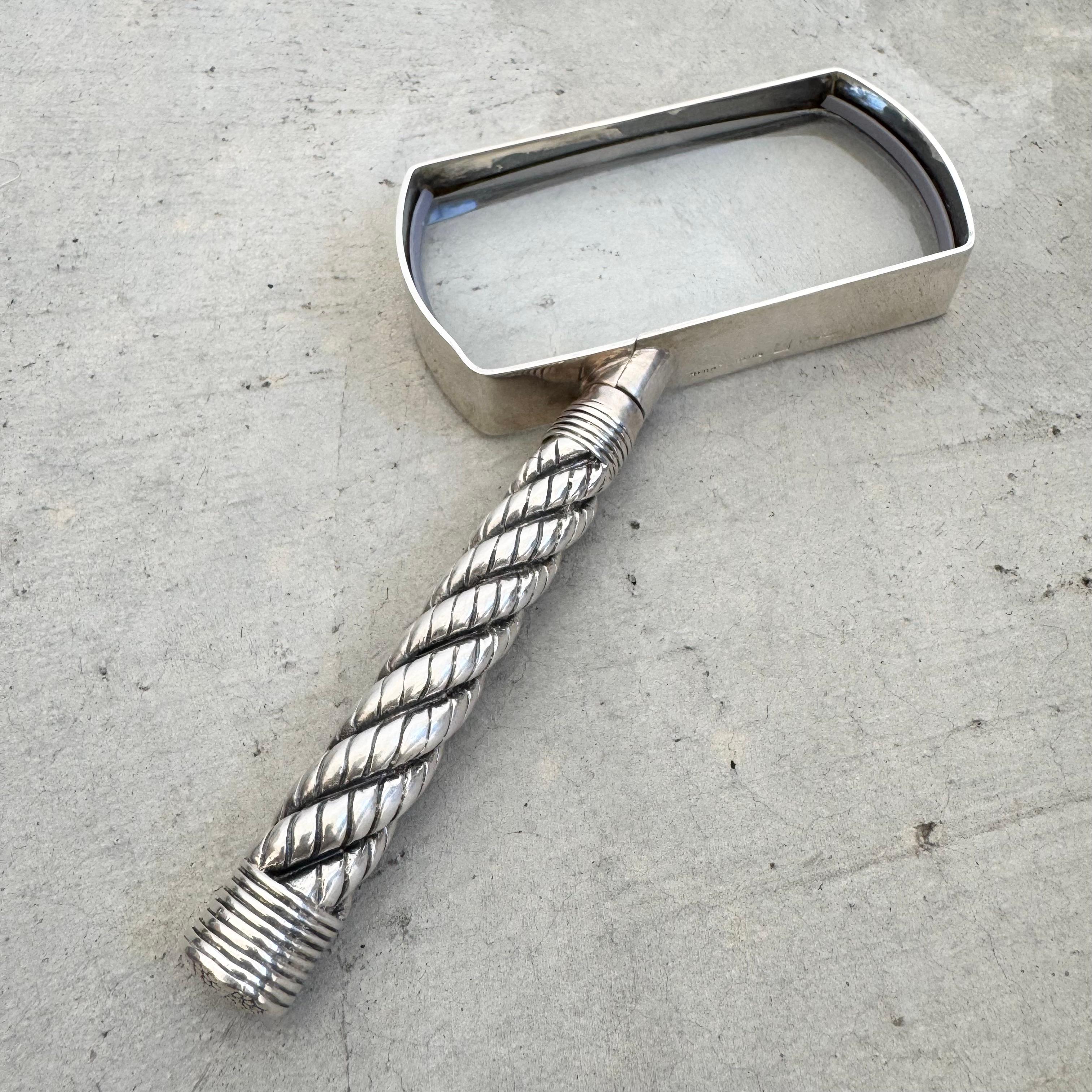 Una magnífica y majestuosa lupa de Hermes en metal fundido con baño de plata. Un asa sobresale en diagonal de la parte inferior del vaso rectangular. La textura de cuerda retorcida se ha convertido en un rasgo emblemático que aparece en los diseños