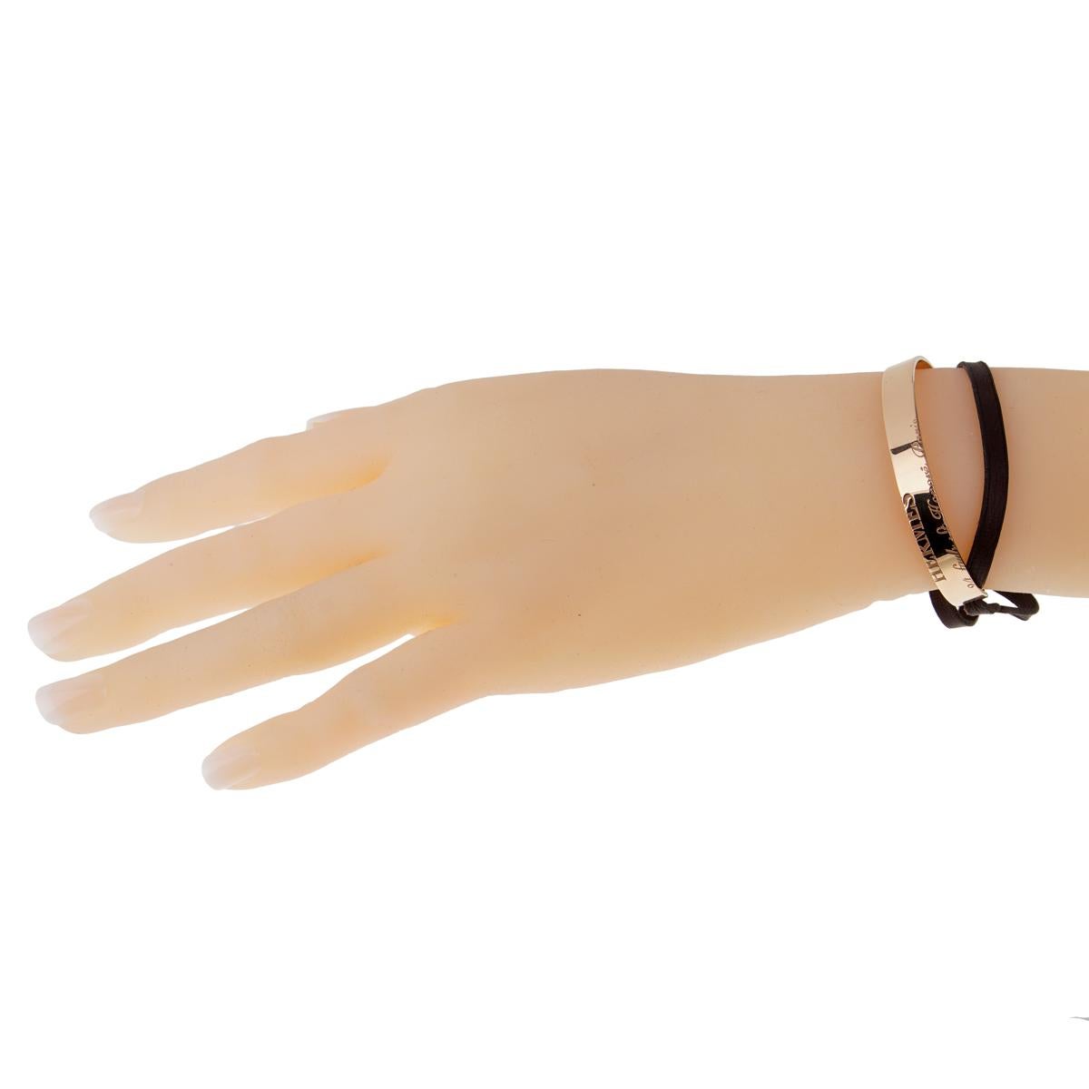 A gorgeous Rose Gold Bangle bracelet from Hermes features engravings of the Hermes logo and chic address in Paris. Made in solid, smooth 18k rose gold, the oval open cuff can be worn alone, or embellished with a chic skinny black leather cord that