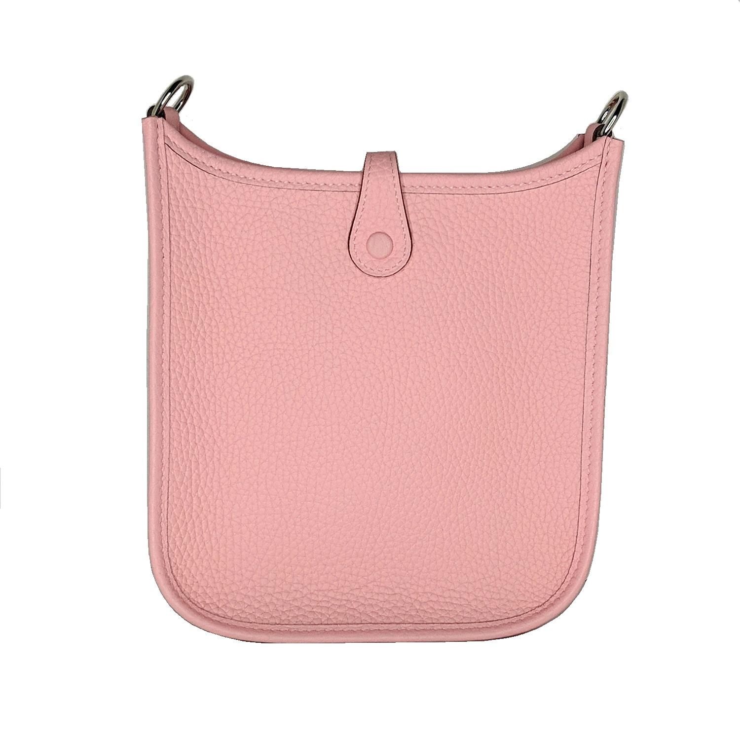 This stylish smaller messenger bag is crafted of textured Taurillon Clemence calfskin leather in pink. It features a perforated Hermes H oval at the front and a canvas crossbody strap with palladium hardware. The top opens with a crossover strap to