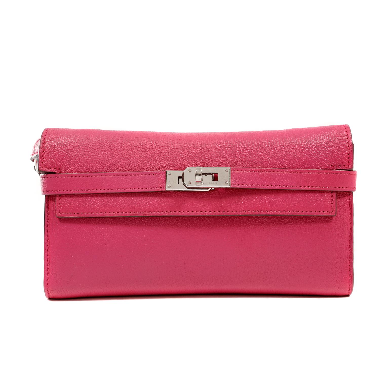 This authentic Hermès Rose Shocking Chevre Kelly Wallet To Go is in excellent condition.   Hand sewn; this stylish wallet is extremely well designed for maximum practicality. Vibrant pink chevre (goat skin) leather long Kelly wallet is textured and