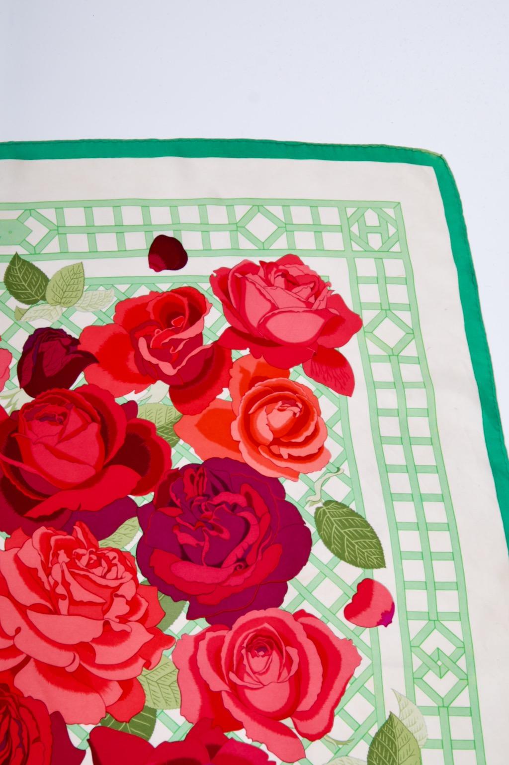 Hermes Roseraie silk scarf designed 1990 by Christiane Vauzelles. Green border and trellis with vivid roses in shades of red and pink spilling from center. 
Some fading at corners, small spot on bottom where edging has unraveled.