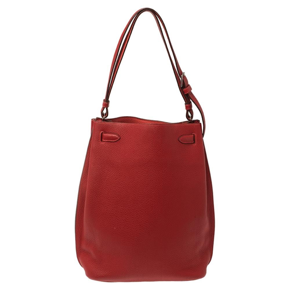 The elegant and timeless elements of the iconic Kelly is coupled with a more casual silhouette in this coveted So Kelly bag. It is crafted from red Togo leather in a slight bucket shape with the signature Kelly lock, in silver-tone on the front and