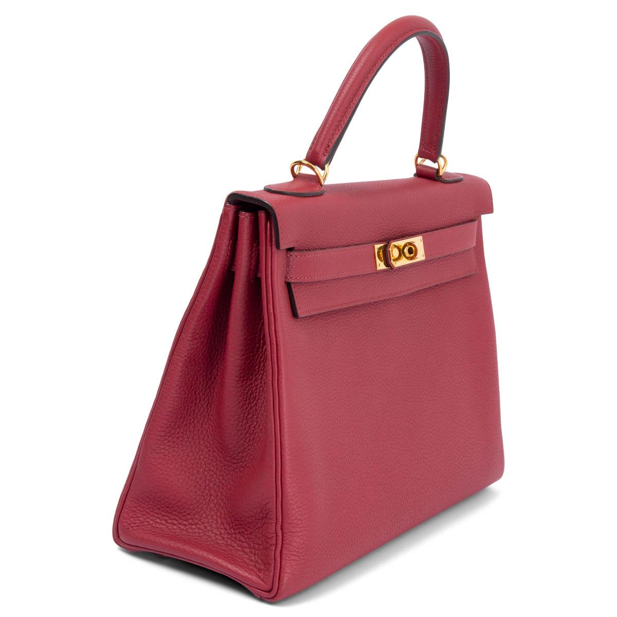 100% authentic Hermès Kelly 32 Retourne bag in Rouge Grenat Veau Togo leather with gold-tone hardware. Lined in Cherve (goat skin) with two open pockets against the front and a zipper pocket against the back. Has been carried and is in excellent