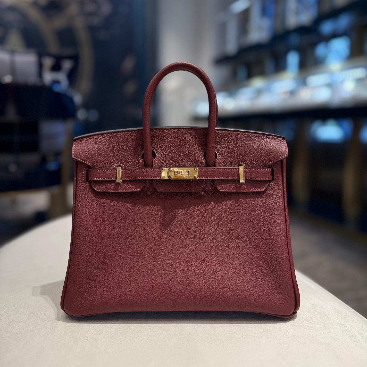 Jewels Aficionado offers an Hermès Rouge H Birkin 25 in Togo leather that is a refined and timeless piece. Its deep burgundy-red hue enhances the classic Birkin design, while Togo leather offers a textured, durable finish with a structured yet