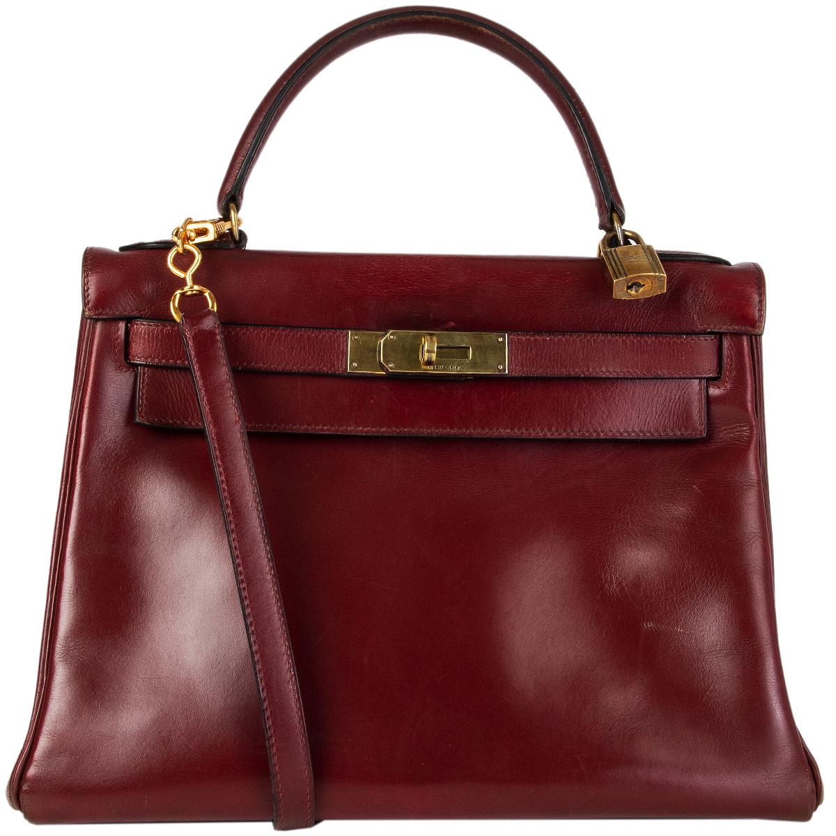 Hermès 'Kelly 28 Retourne' in burgundy Veau Box. Vintage 1970. Lined in Chevre (goat skin) with two open pockets against the front and a open pocket against the back. Has been carried with overall signs of use, wear to the bottom corners and faint