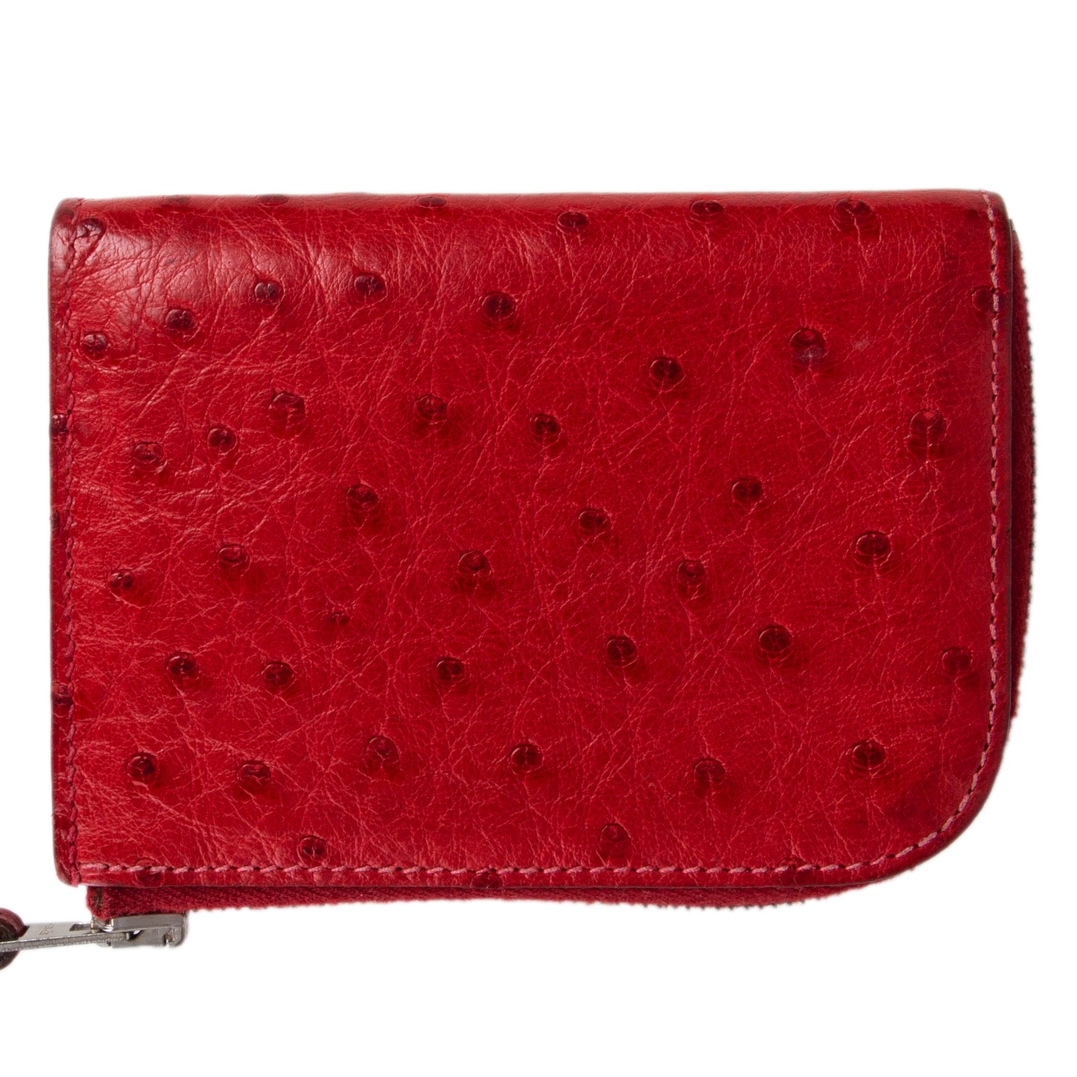 Hermes zip wallet on a strap in Rouge VIF (red) Ostrich leather. Closes with a zip. Lined in Chevre (goat skin) with six credit card slots. Has been carried with some minor patina. Overall in excellent condition.

Width 10cm (3.9in)
Height 7.5cm