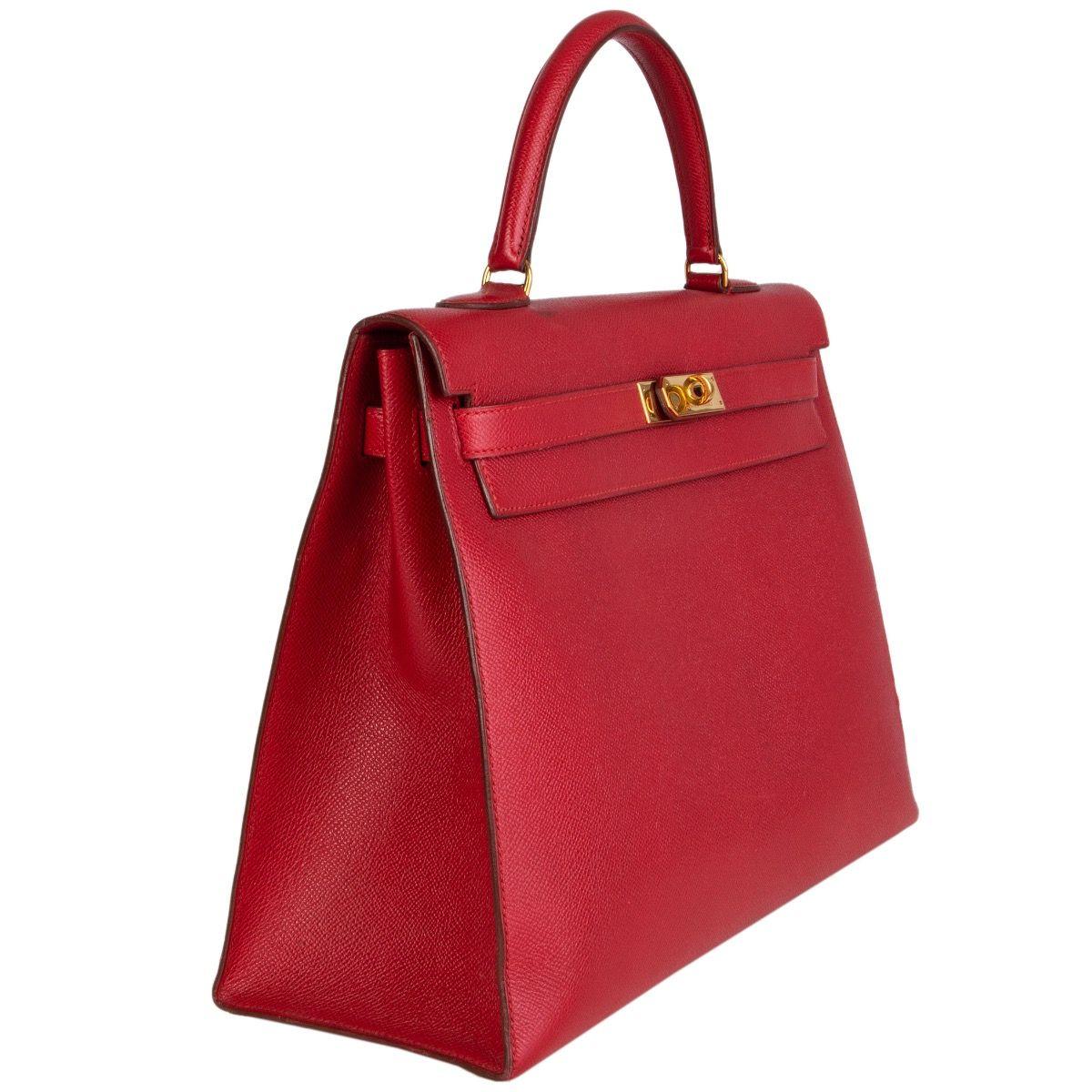 Hermès 'Kelly I 35' Sellier bag in Rouge Vif Veau Courchevel with gold-plated hardware. Removable shoulder strap. Closes with a turn-lock and straps on the front. Lined in Chevre (goat skin) with two open pockets against the front and a zipper