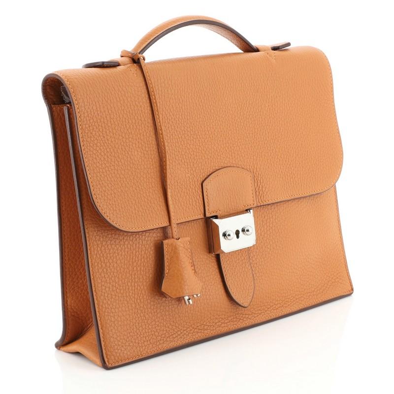 This Hermes Sac a Depeches Bag Clemence 27, crafted from Orange H orange clemence leather, features flat top handle, accordion side gussets, and palladium hardware. Its flip lock closure opens to an Orange H orange clemence leather interior with two