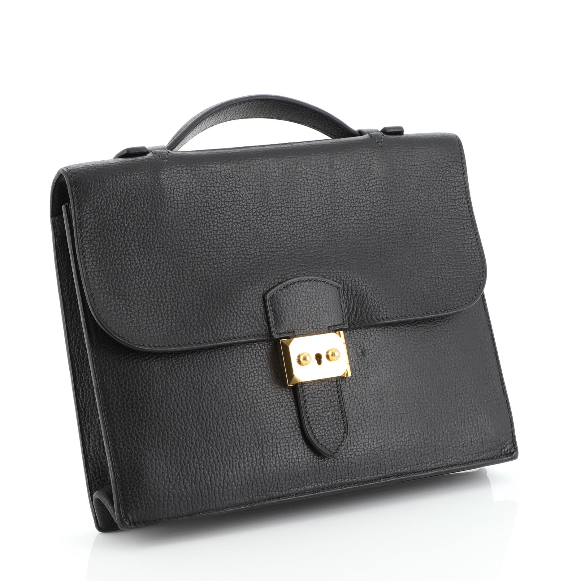 This Hermes Sac a Depeches Bag Togo 27, crafted from Noir black Togo leather, features flat top handle, accordion side gussets, and gold hardware. Its flip lock closure opens to a Noir black raw leather interior with two main compartments and slip