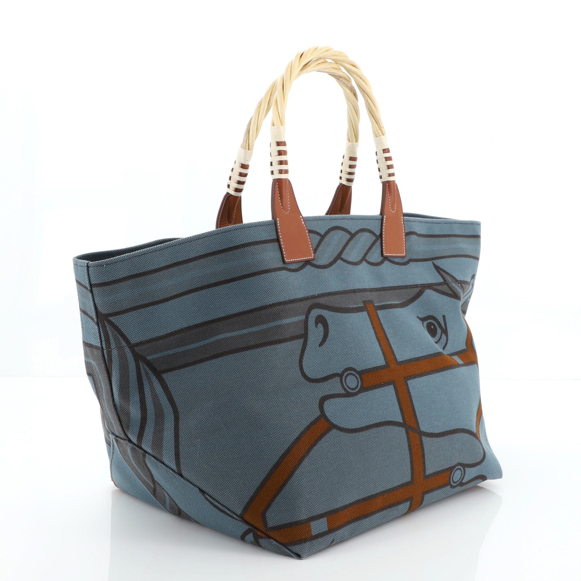 This Hermes Sac Steeple Tote Printed Toile with Wood, crafted from multicolor printed colvert Toile H and Fauve Barenia leather, features a graphic print design, dual wood top handles, and wood hardware. It opens to a colvert blue Toile H interior.