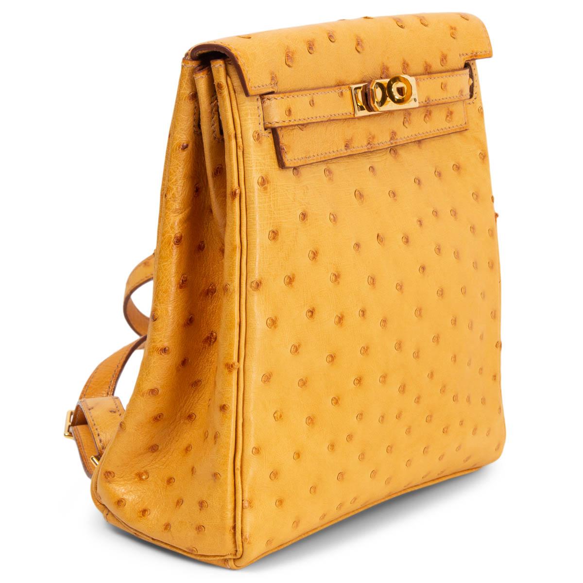 100% authentic Hermès Kelly A Dos backpack in Saffron ostrich leather featuring gold-tone hardware and classic Kelly belt-style closure. Has two adjustable backpack straps and is lined in Saffron Chevre leather with one slip pocket against the back.