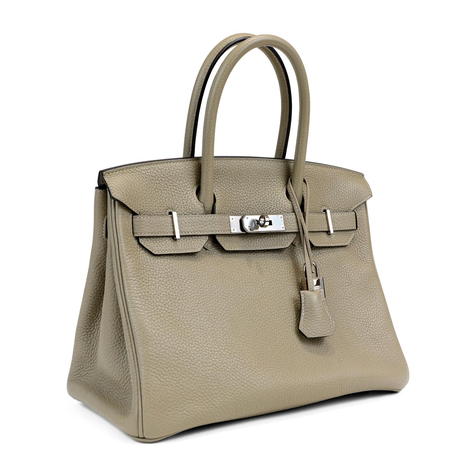 This authentic Hermès Sage Togo Leather 30 cm Birkin Bag is in pristine unworn condition with the protective plastic intact on the hardware.  Waitlists exceeding a year are commonplace for the intensely coveted Birkin.  Each piece is hand crafted by