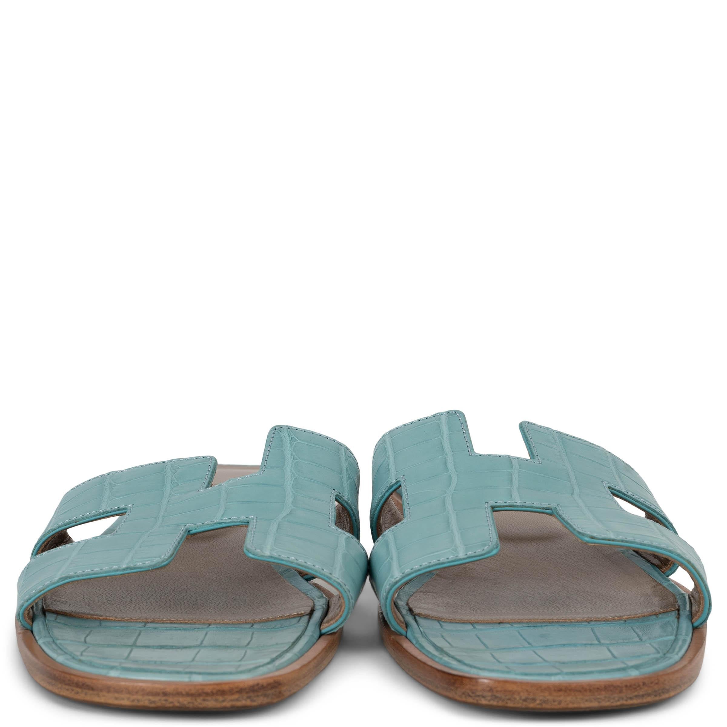 These 100% authentic Hermès Oran slide sandals in Bleu Saint Cry blue matte alligator embody the brand’s signature elegance and craftsmanship. Featuring the iconic H cut-out front, these slides offer a sleek, minimalist design in luxurious alligator