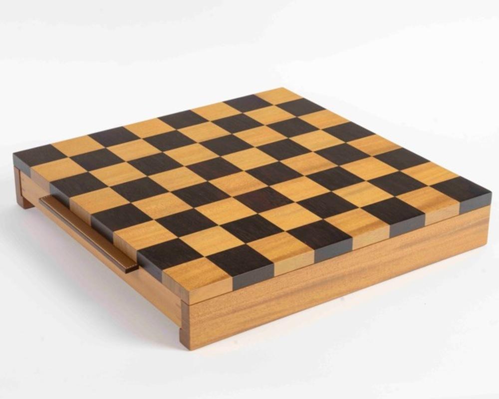 Chess set in natural mahogany and cassia

- Handles in saddle-stitched H-shaped bull calf leather
- Pieces in solid natural mahogany and cassia, weighted with stainless steel and engraved with a saddle nail

Made in Indonesia

Designed by Studio