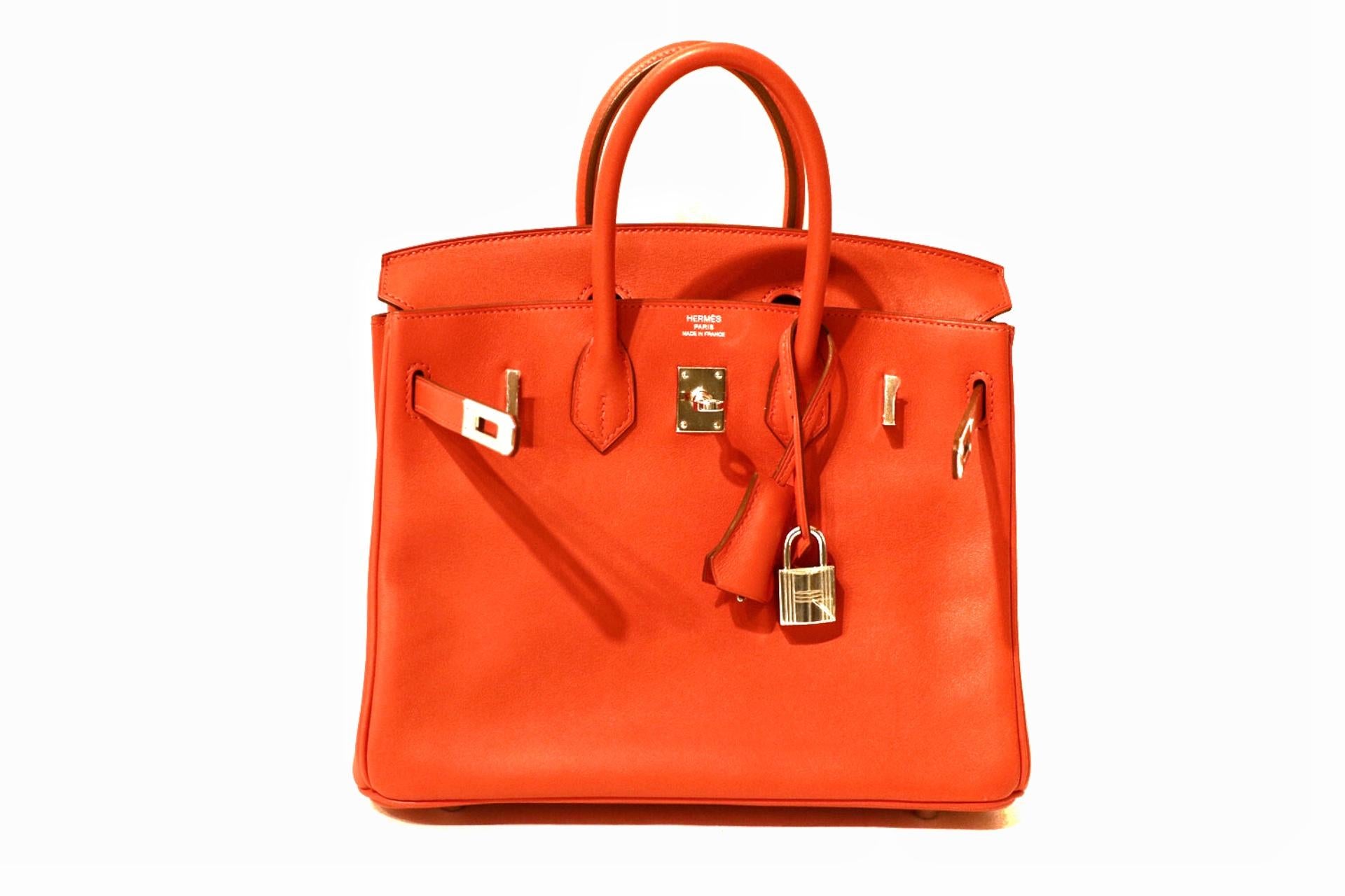 This authentic Hermès Sanguine Swift Leather 25 cm Birkin Bag is in pristine unworn condition with plastic intact on the hardware.
Waitlists exceeding a year are commonplace for the intensely coveted classic leather Birkin bag.  Each piece is hand