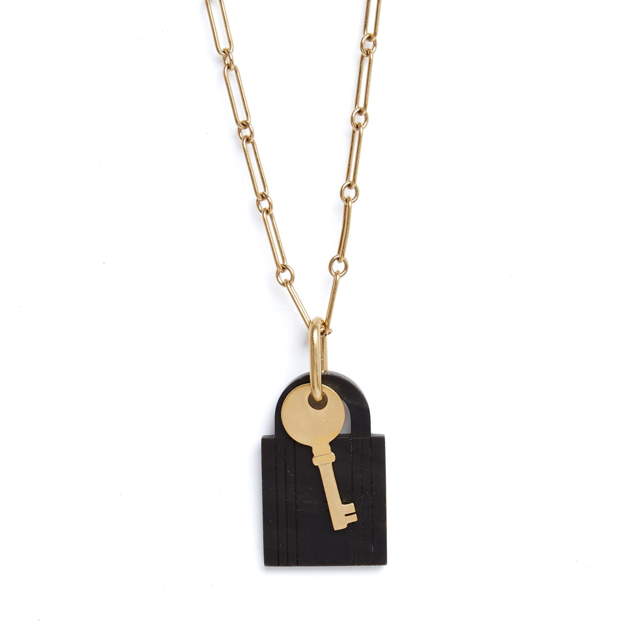 Collana Hermès modello Amulette Padlock ciondolo GM formato da una lunga catena in metallo placcato oro con un doppio ciondolo raffigurante il famoso lucchetto della borsa Kelly in corno naturale e la sua chiave in metallo placcato oro, firma a