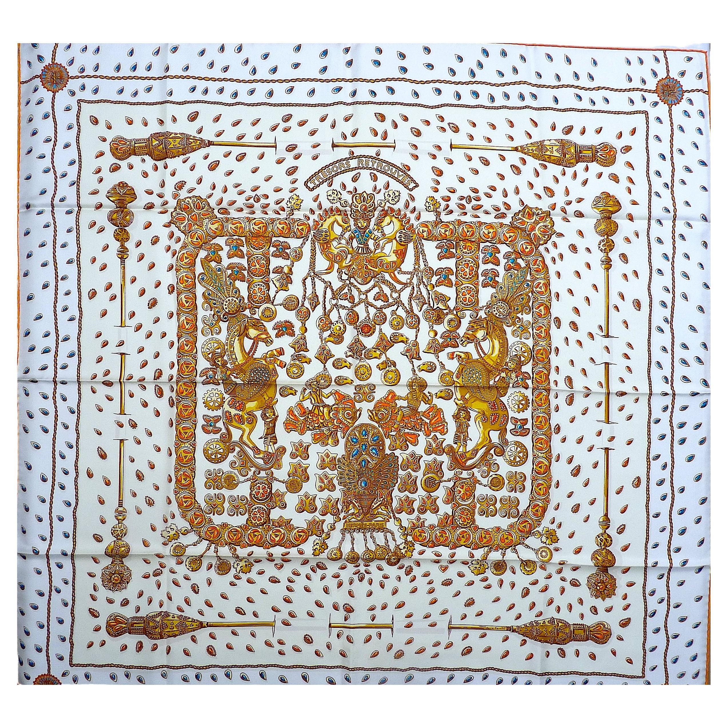 Splendida sciarpa di seta HERMES 35 X 35 pollici BRAND NEW nella sua scatola, intitolata Trésors Retrouvés, disegnata da Annie Faivre, con sfondo bianco e motivi oro, arancione e blu, con orli arancioni a contrasto.
Annie Faivre ha composto uno