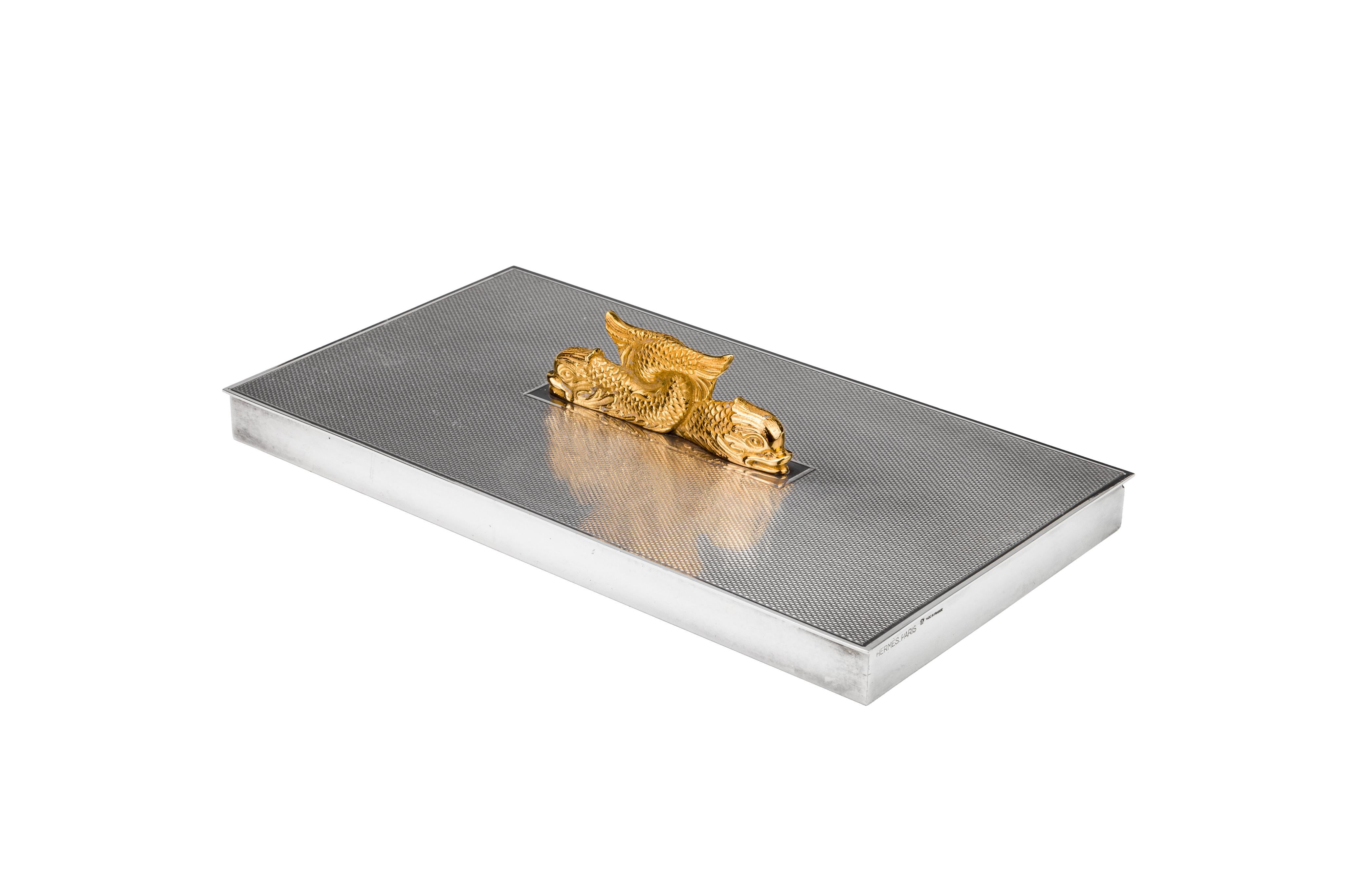 A fine and elegant box by Hermes with a set of gilted serpent's interlocking set atop. The top of the box is finished with an engine-turned texture.

Sleek and finely crafted. This will make a great addition to any surface.


 