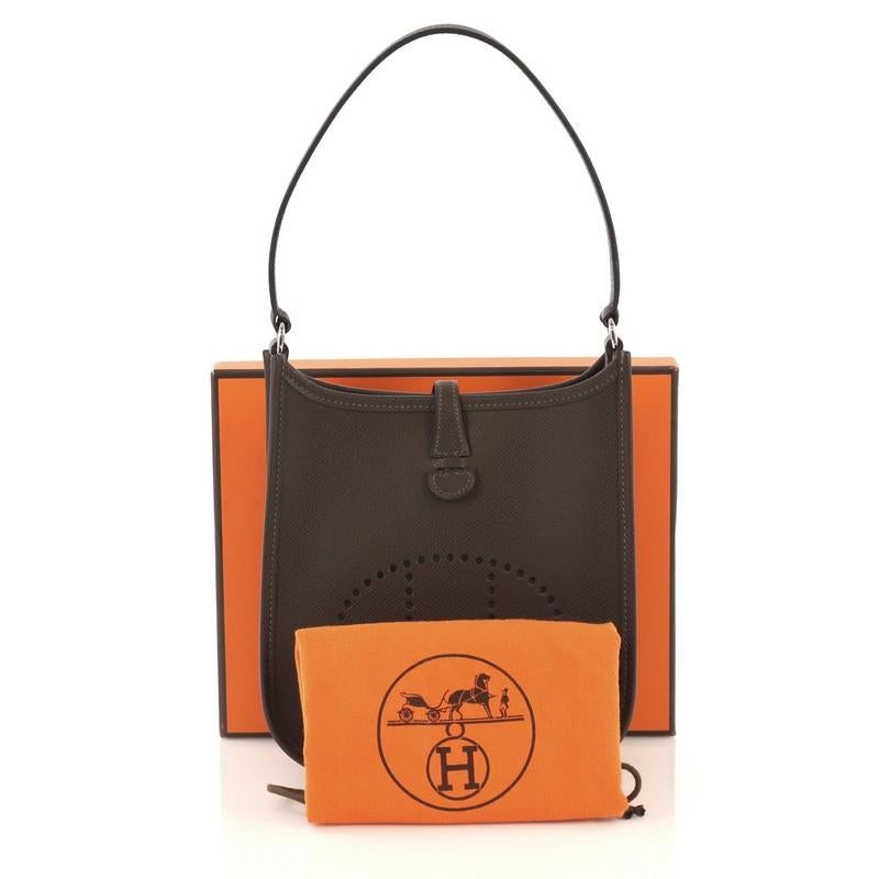 This Hermes Short Strap Evelyne Shoulder Bag Epsom TPM, crafted from Chocolate brown Epsom leather, features a perforated H design at the front, flat leather strap, and palladium hardware. It opens to a Chocolate brown raw leather interior. Date