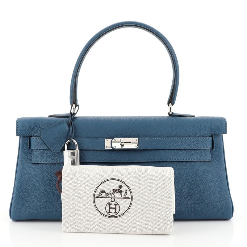 This Hermes Shoulder Kelly Handbag Togo 42, crafted in Bleu Izmir blue Togo leather, features single rolled top handle, frontal flap, and palladium hardware interior. Its turn-lock closure opens to a Bleu Izmir blue Chevre leather interior with zip