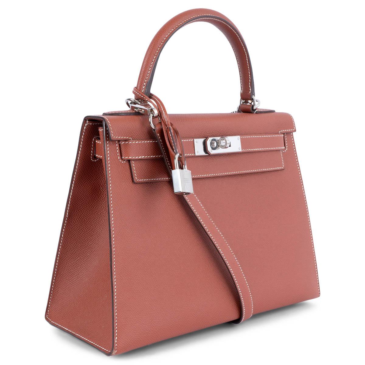 100% authentic Hermès Kelly 28 Sellier bag in Sienne (brick) Veau Epsom featuring contrasting white stitching and palladium hardware. Lined in Chevre (goat skin) with an open pocket against the front and a zipper pocket against the bag. Has been