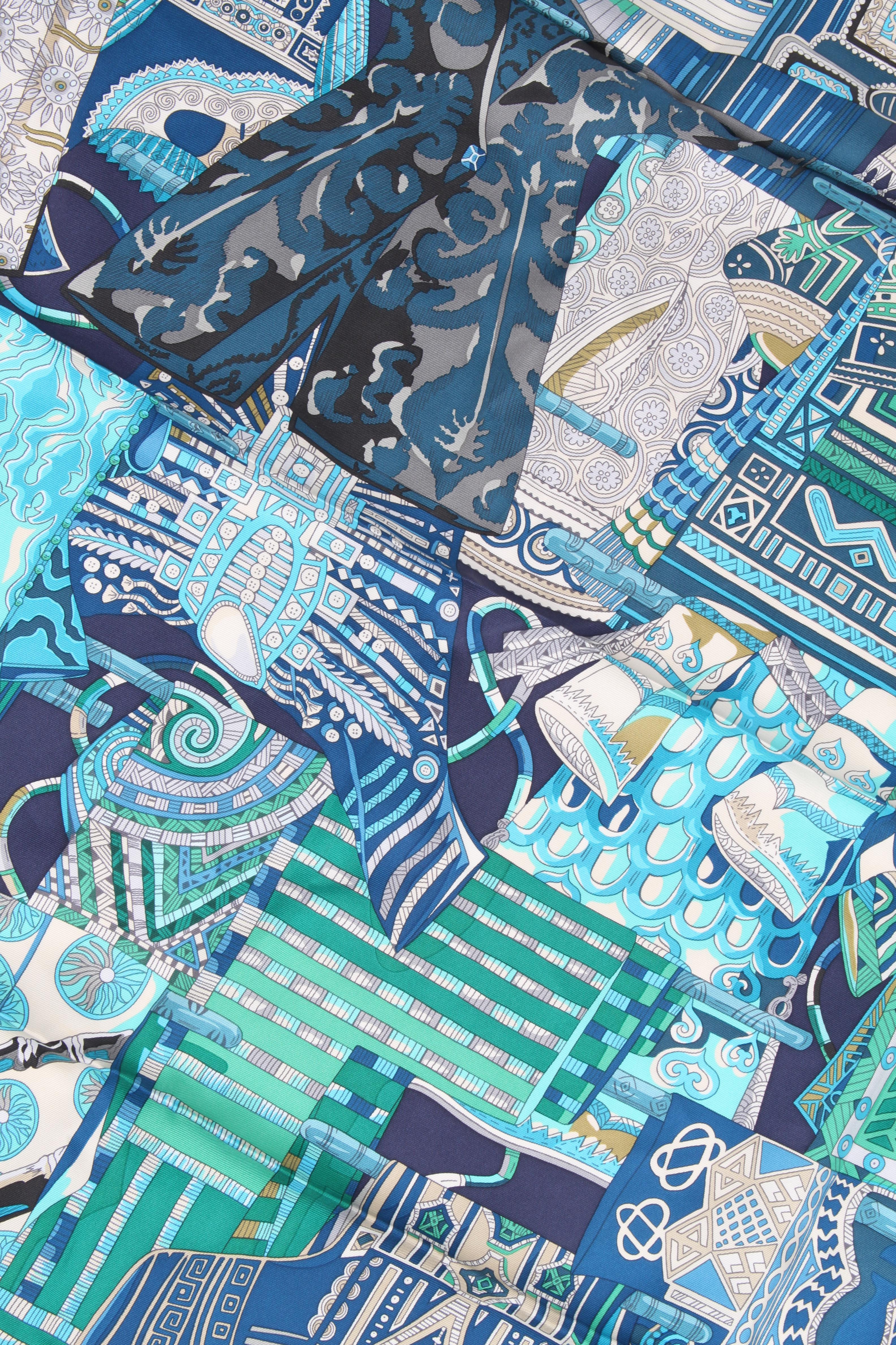 This fantastic silk scarf by Hermes is covered with a print in a blue color scheme on a dark blue foundation.

Name: Voyage en Étoffes
Measurements: 90 x 90 centimeters
Colors: blue, turquoise, green, white
Material: silk
Condition: like new,