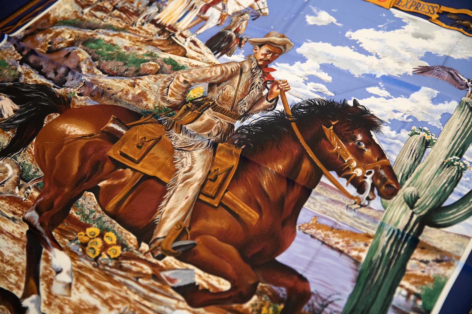 Pañuelo de seda azul marino coleccionable Hermès Pony Express by Kermit Oliver. Bordes enrollados a mano. Tema muy coleccionable . Consulta las dos últimas fotos para ver los pequeños defectos. Una mancha descolorida y dos pequeños hilos