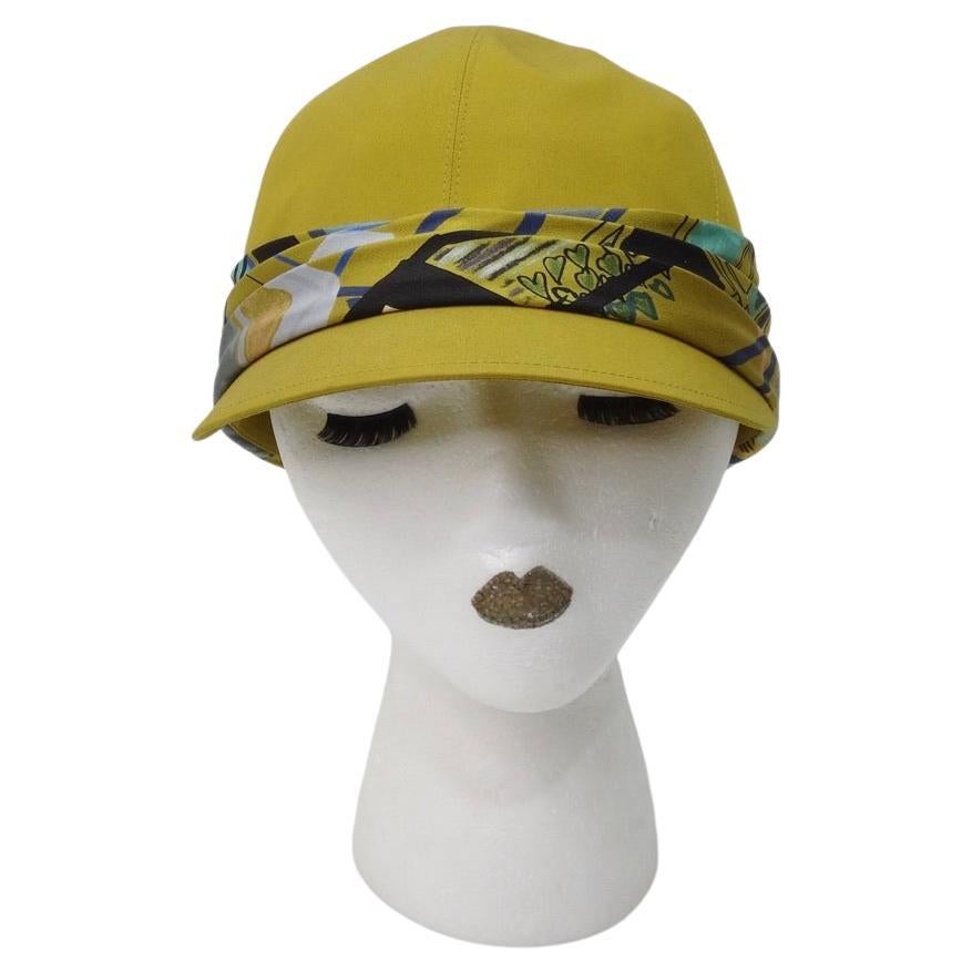 Keep the sun at bay in this green Hermes cap featuring printed silk wrapped around the base. The style of this hat is so flattering and classy in a super round shape with a short visor. Match this to your favorite cool toned Chanel dress for a