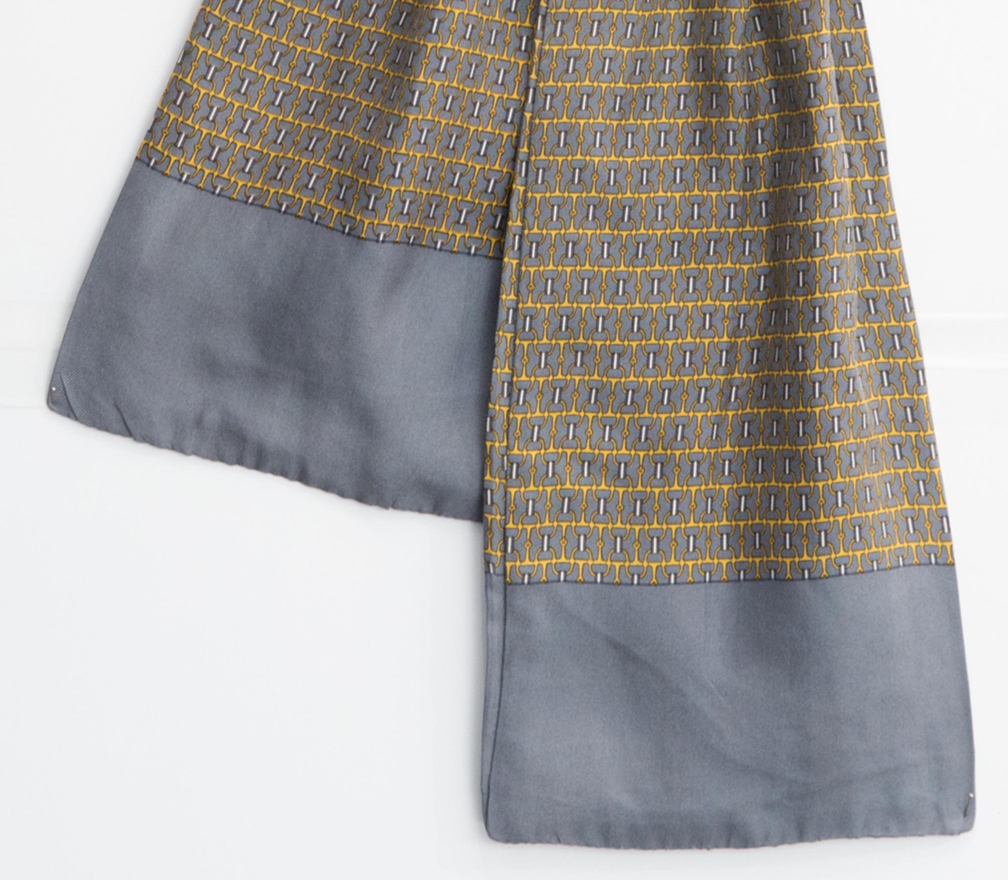 Hermes grey silk scarf ascot  featuring an all-over print, a grey border and a center pleat. 
Circa 1990s
In good vintage condition. Made in France.
44in. (112 cm)  X 6.7in. (17cm)
We guarantee you will receive this  iconic item as described and