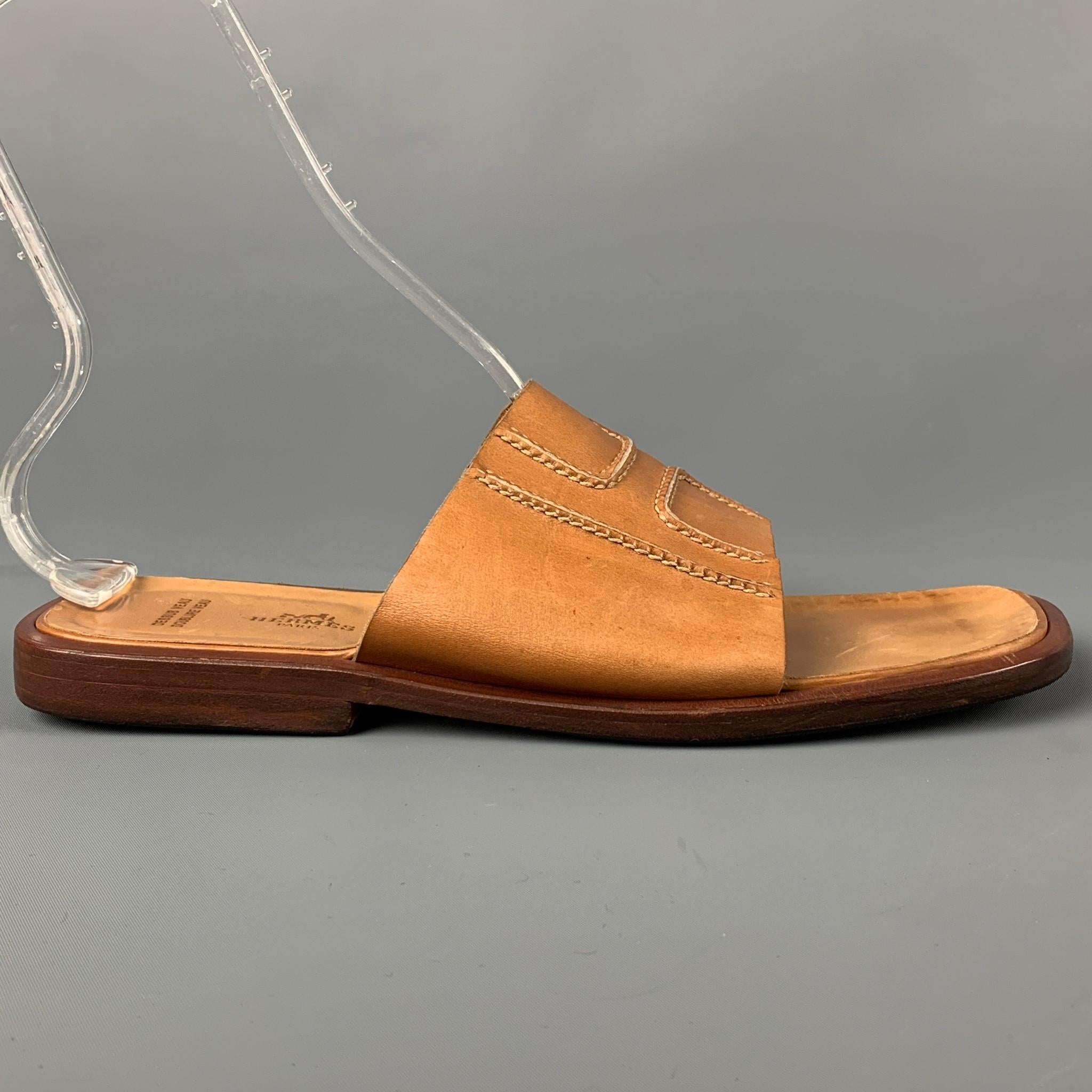 HERMES sandals comes in a tan leather featuring a 'H' stitched design and a slip on style. Made in Italy. 

Good Pre-Owned Condition.
Marked: 45

Outsole: 11.5 in. x 4.5 in. 