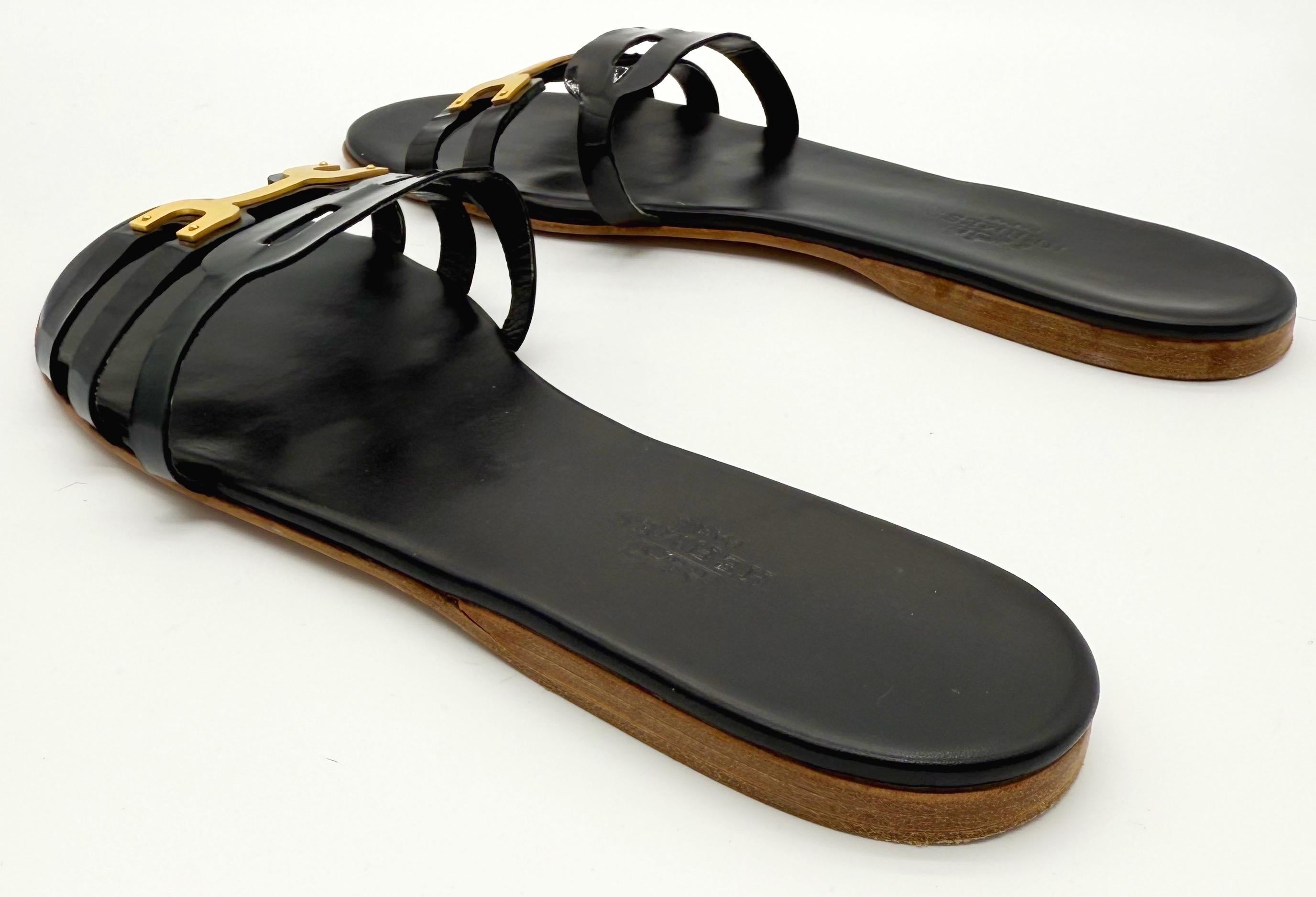 Schicke 2000er Hermes Sandalen aus schwarzem Lackleder mit goldener Hardware. Gleitet einfach über den Fuß. Kann leicht nach oben oder unten gekleidet werden. Kombinieren Sie ihn mit Jeans, Shorts, Hosen oder einem Kleid.
In gutem, leicht getragenem