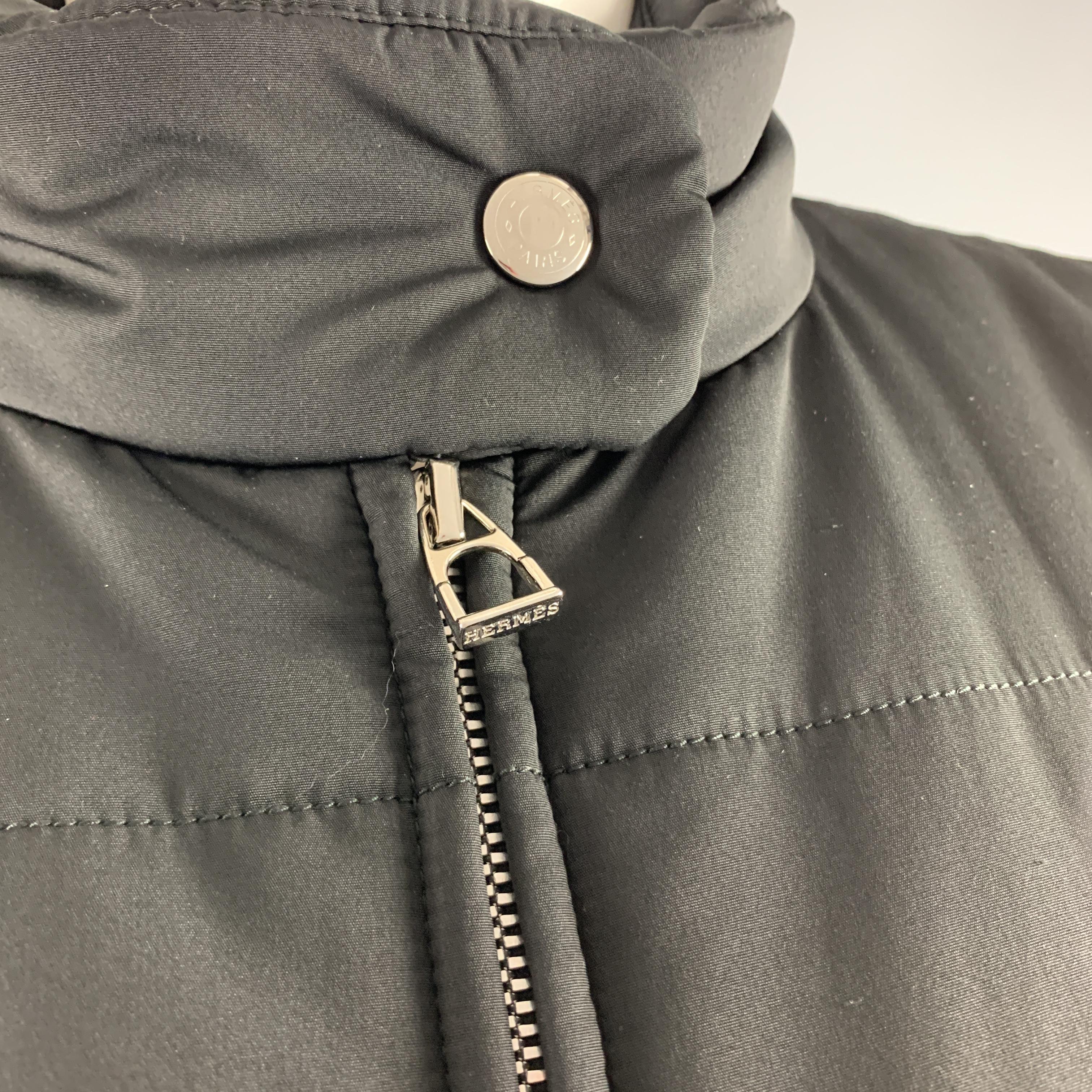 HERMES cropped Jockey Technical Jacket comes in quilted padded nylon with a high snap collar, double zip front, and zip pockets. Made in Italy.

Excellent Pre-Owned Condition.
Marked: XS

Measurements:

Shoulder: 14 in.
Bust: 37 in.
Sleeve: 25