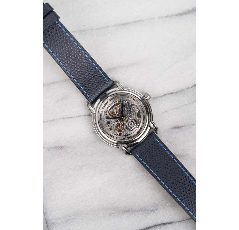 Aquí tienes un Hermes París Esqueleto referencia SM1-790 Squelette con esfera esqueleto de acero inoxidable de la década de 2000. Mantiene la hora y es totalmente funcional.  Las medidas incluyen una caja de 35 mm de ancho y una orejeta de 18 mm. En
