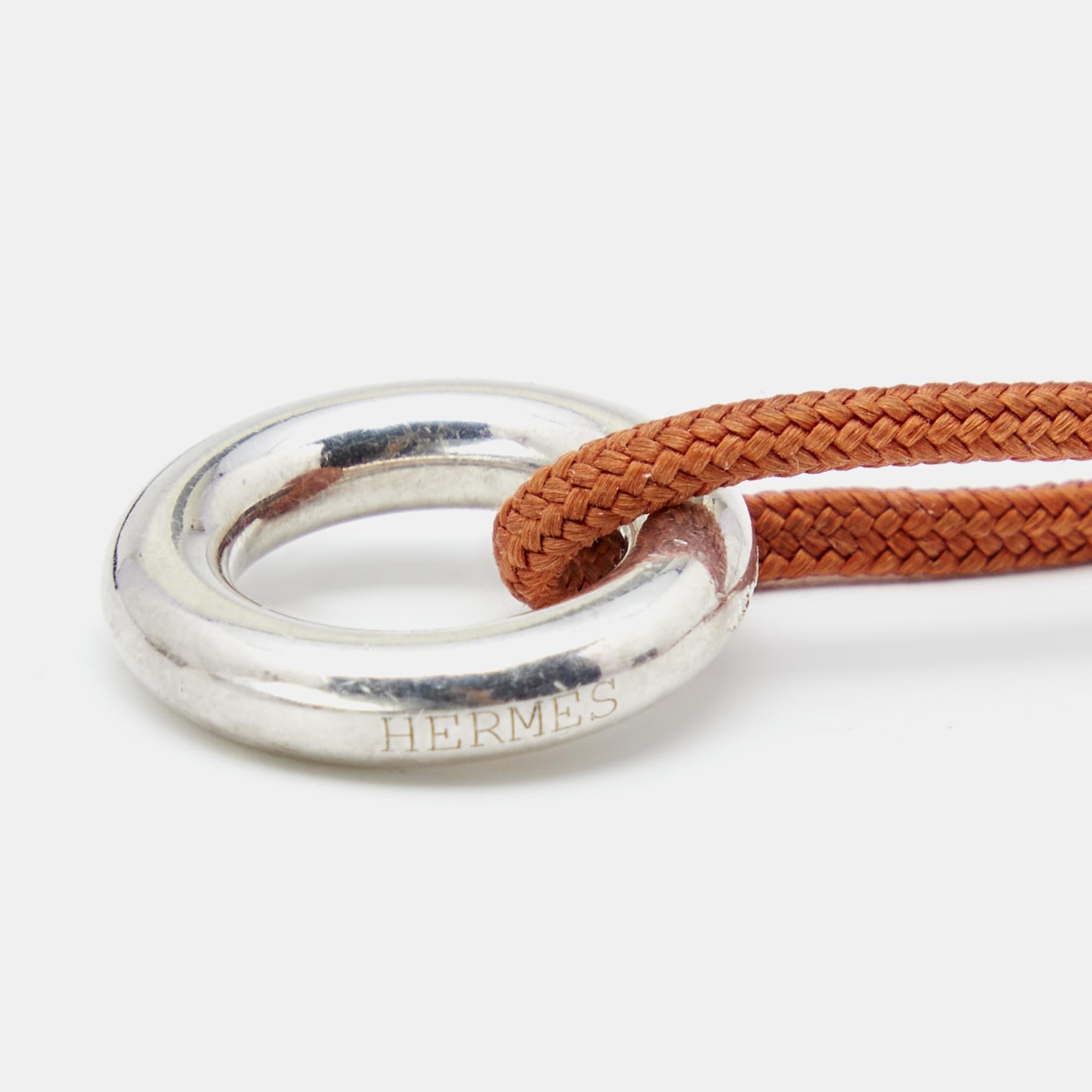 Exuding glamour and classic style, this wrap bracelet from Hermès is something you'll love having around your wrist. It is a Sterling silver creation that is enhanced with an orange cord and a toggle fastening It flaunts signature brand engravings.