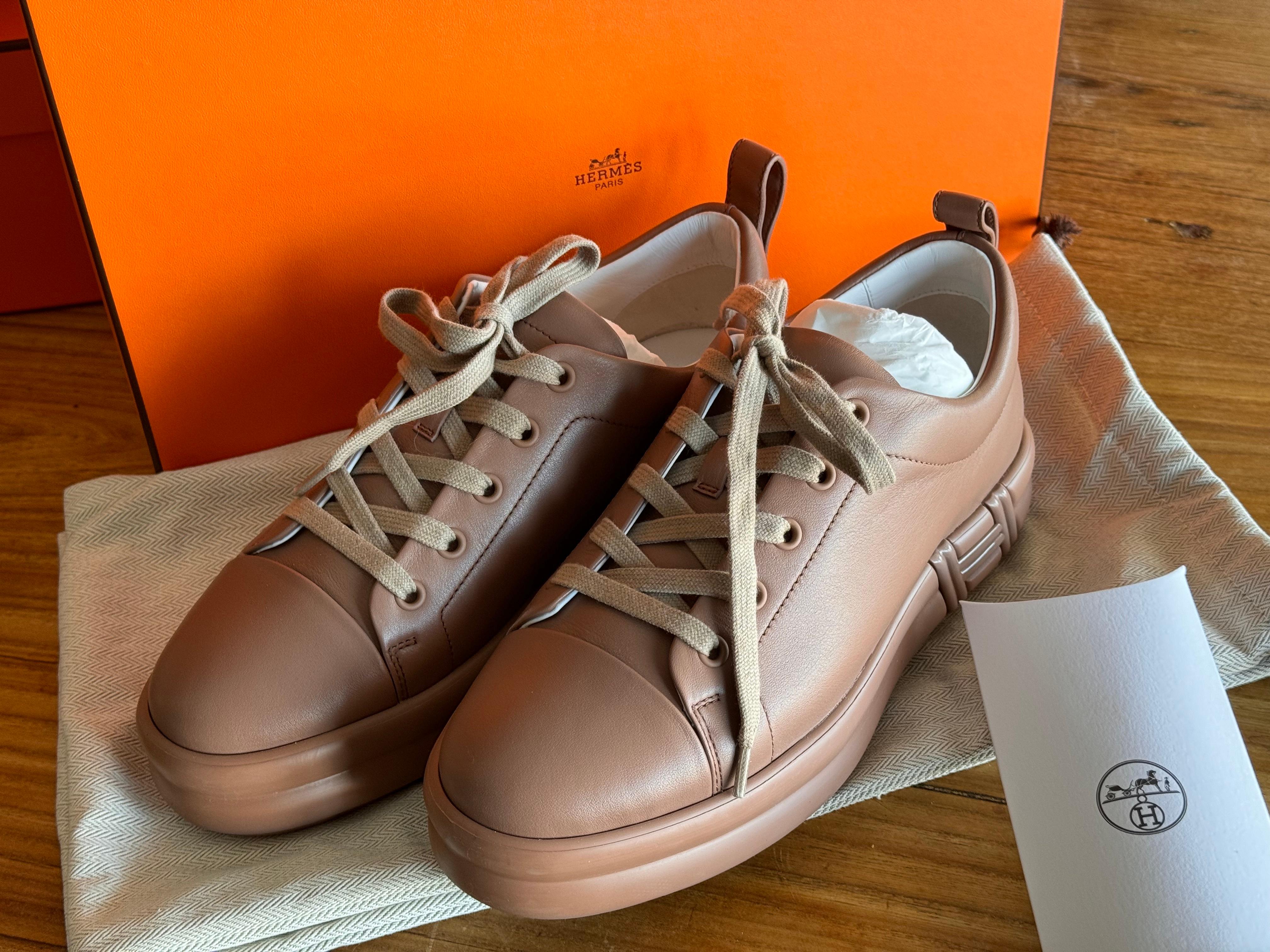 Introducing Hermes’ luxurious leather sneaker, the Femme Happy, in the exquisite Rose Perle color, now available in size 38. Each pair is meticulously presented in its original box, complete with a dust bag for storage and an extra set of shoelaces