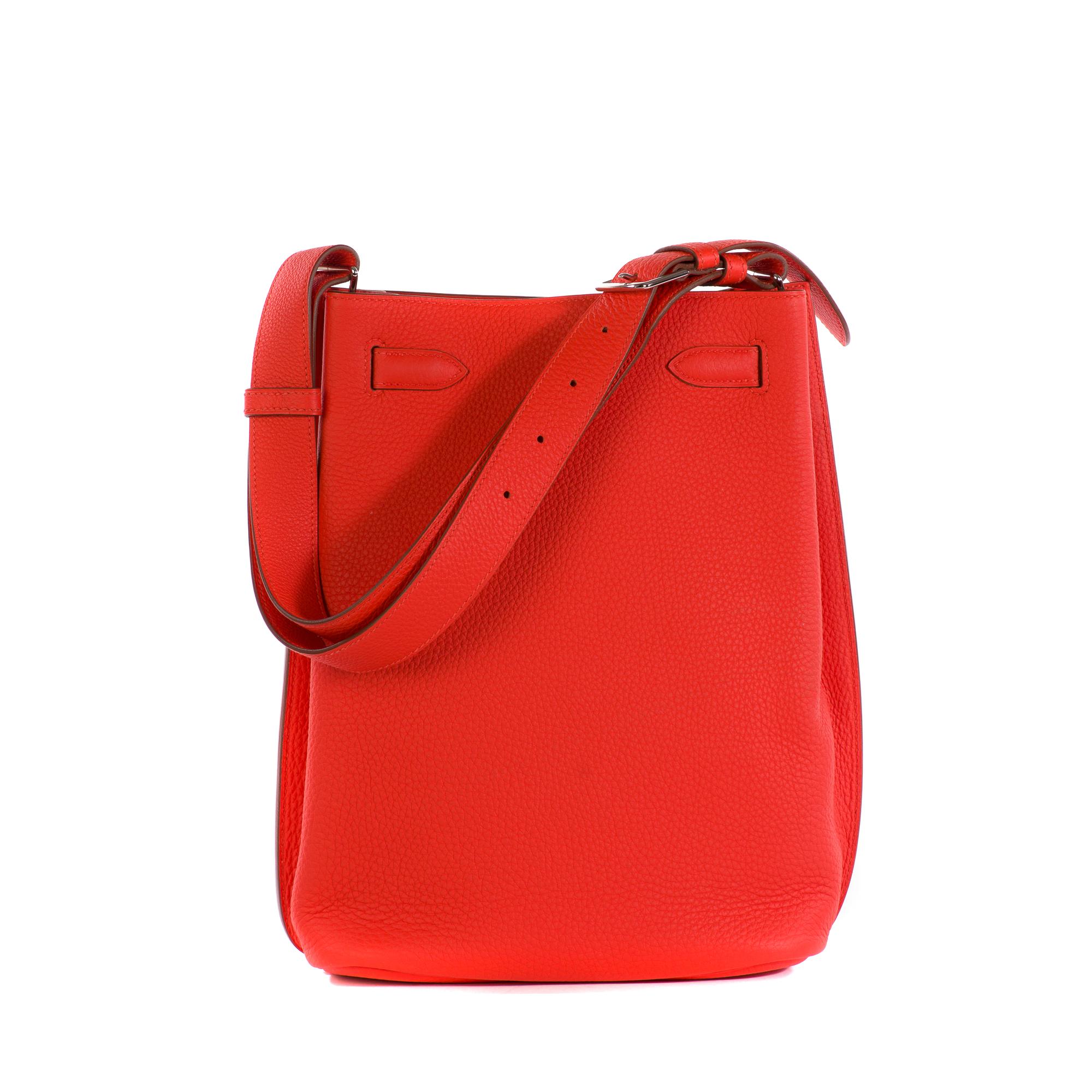 Hermes So Kelly Handbag Togo 22, crafted from red Togo leather, features an adjustable single looped handle and palladium-tone hardware. Its turn-lock closure opens to a blue leather interior with side zip and slip pockets. 
Made in France
Stamp : Q