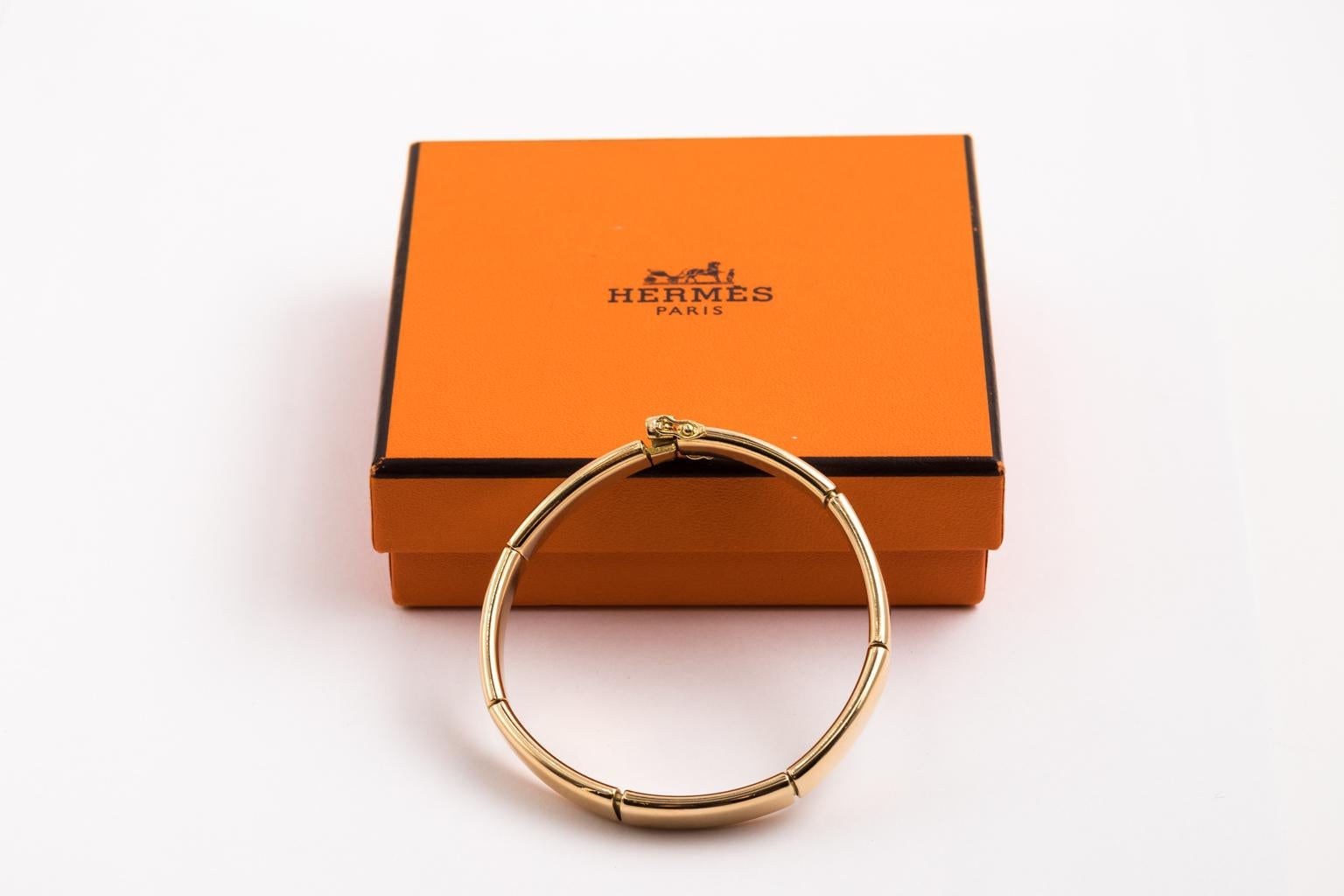 Bangle bracelet designed by Hermes with a simple design. It is crafted from 18k yellow gold with a high polished finish. Each bangle is 7.5 mm wide and 3 mm thick. There are 7 24 mm sections that are linked with a mechanism that allows the bangle