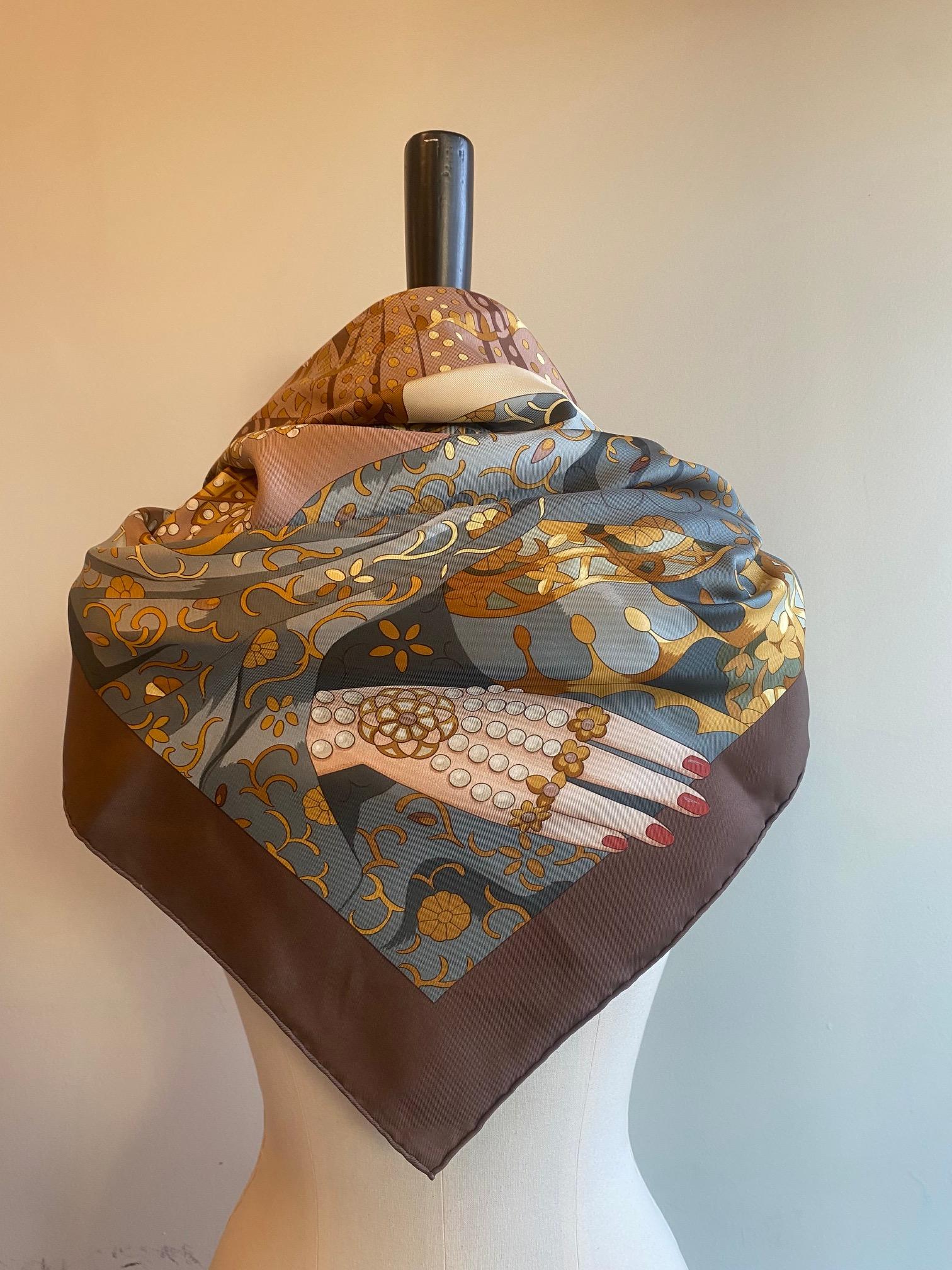 Rare silk scarf from Hermes. Designed by Cathy Baschet in 1996, the 'Splendeur des Maharajas II' depicts a large, regal woman in traditional dress sitting inside an opulent palace complete with musicians with sitars and dancers. In tones of brown,