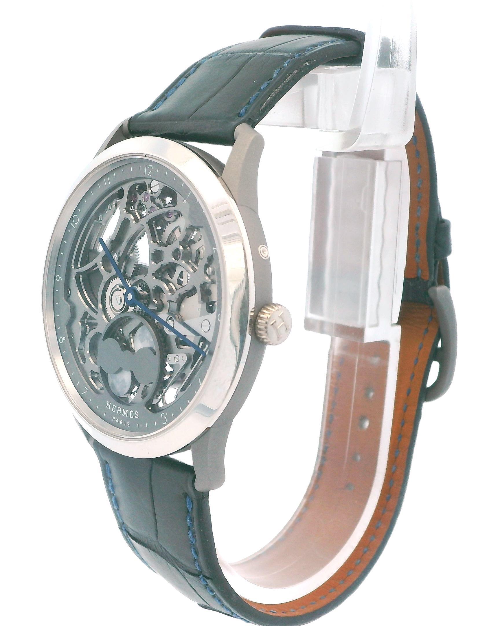 Un sofisticato orologio scheletrato di Hermès, con cassa rotonda in titanio da 39 mm e fondello da esposizione. Il movimento automatico è visibile attraverso l'intricato quadrante scheletrato. Completato da un cinturino in pelle nera, questo