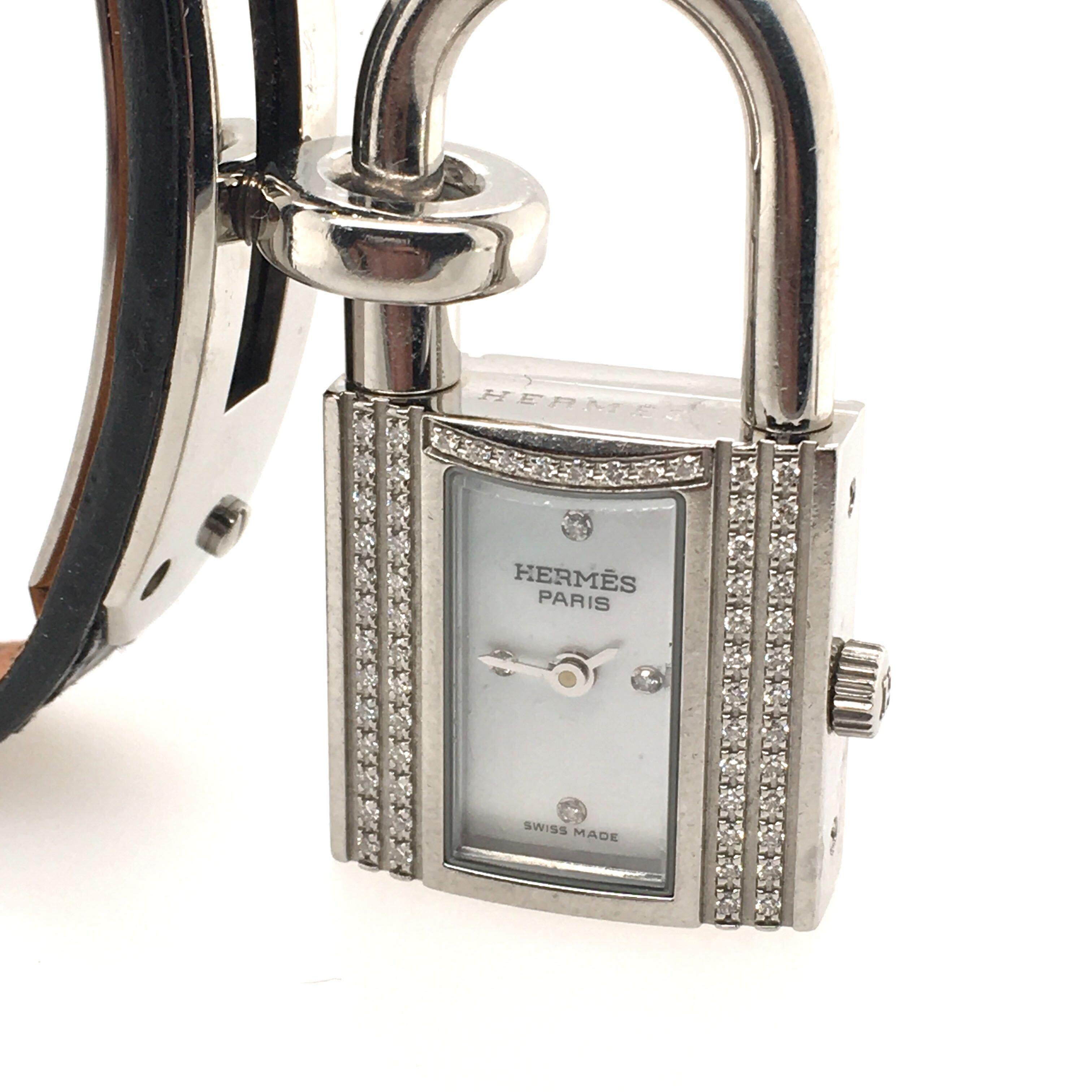 Eine Kelly Watch aus Edelstahl mit Diamanten. Hermes. Von Quarzwerk, 20mm. Das Schloss ist mit einer Uhr versehen, das weiße Zifferblatt mit einseitig geschliffenen Diamanten bei 12, 3, 6 und 9 Uhr, das Gehäuse mit eingefassten Diamanten verziert,