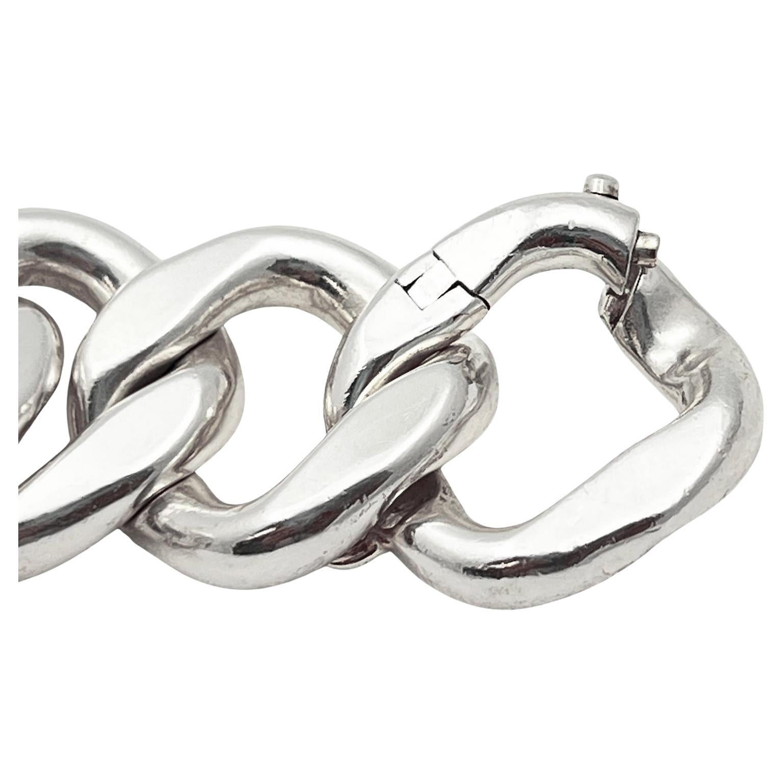 Hermès  'Agora' curb-link design bracelet in sterling silver.  Bold polished curb design with larger open 37.84mm central link and twelve smaller links approximately 21.11mm each. One hinged end link serves as the clasp and opens with push tab. 