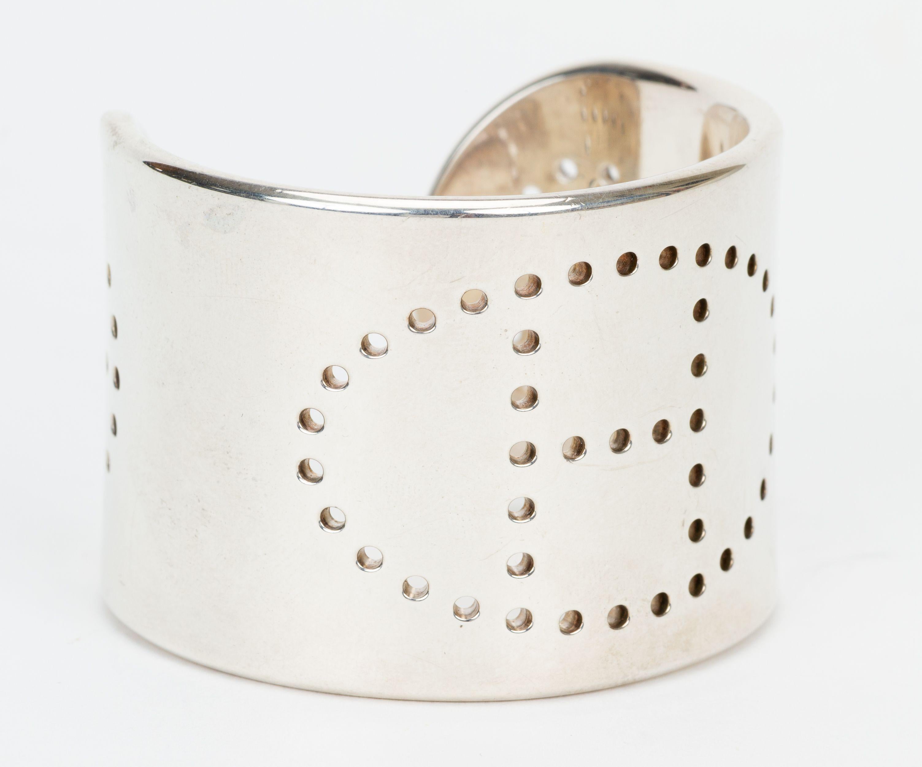 The Hermès Sterling Silver Eclipse Cuff is a wide cuff bracelet crafted of genuine sterling silver and features a perforated H design, reminiscent of the Evelyne handbag. Extra small size.