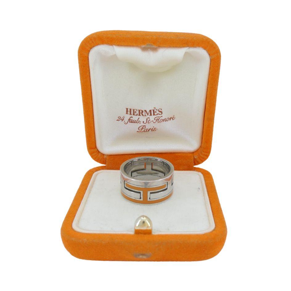 ChatGPT ha detto:

Questo autentico anello con motivo H di Hermès presenta un audace design geometrico in argento sterling con un vivace intarsio di smalto arancione. Realizzato intorno al 2004, l'ampia fascia mostra il caratteristico motivo a 