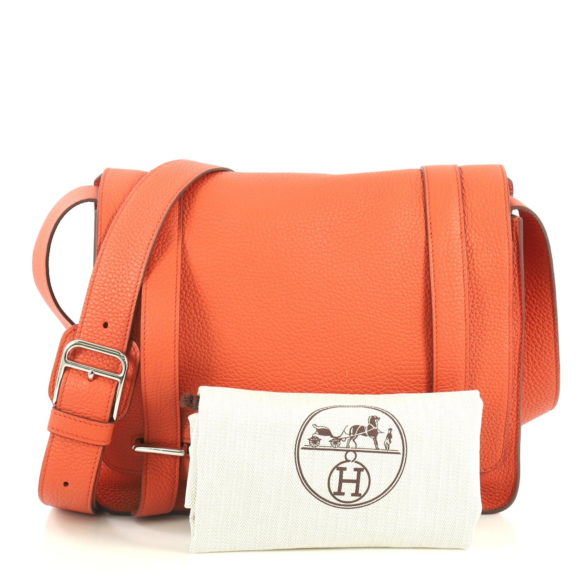 This Hermes Steve Caporal Handbag Clemence, crafted in Terre Battue orange Clemence leather, features an adjustable leather strap and palladium hardware. Its bracket closure opens to a Terre Battue orange Chevre leather interior with slip pocket.