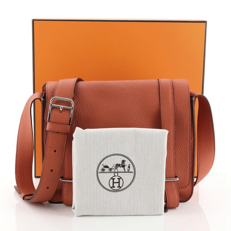 Ce sac Hermes Steve Caporal Handbag Clemence:: réalisé en cuir Terre Battue orange Clemence:: est doté d'une sangle en cuir réglable et de pièces en palladium. Sa fermeture à crochet s'ouvre sur un intérieur en cuir Chevre orange Terre Battue avec