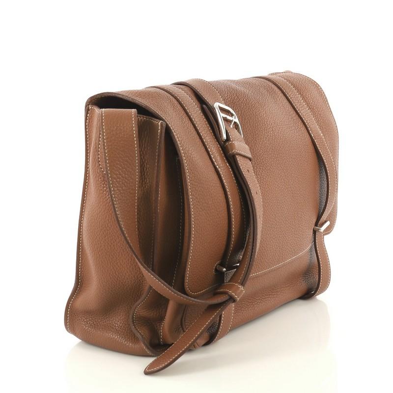 This Hermes Steve Messenger Bag Clemence 35, crafted in Gold brown Clemence leather, features an adjustable leather strap, slip pocket under flap, and palladium hardware. Its bracket closure opens to a Gold brown Chevre leather interior with zip and