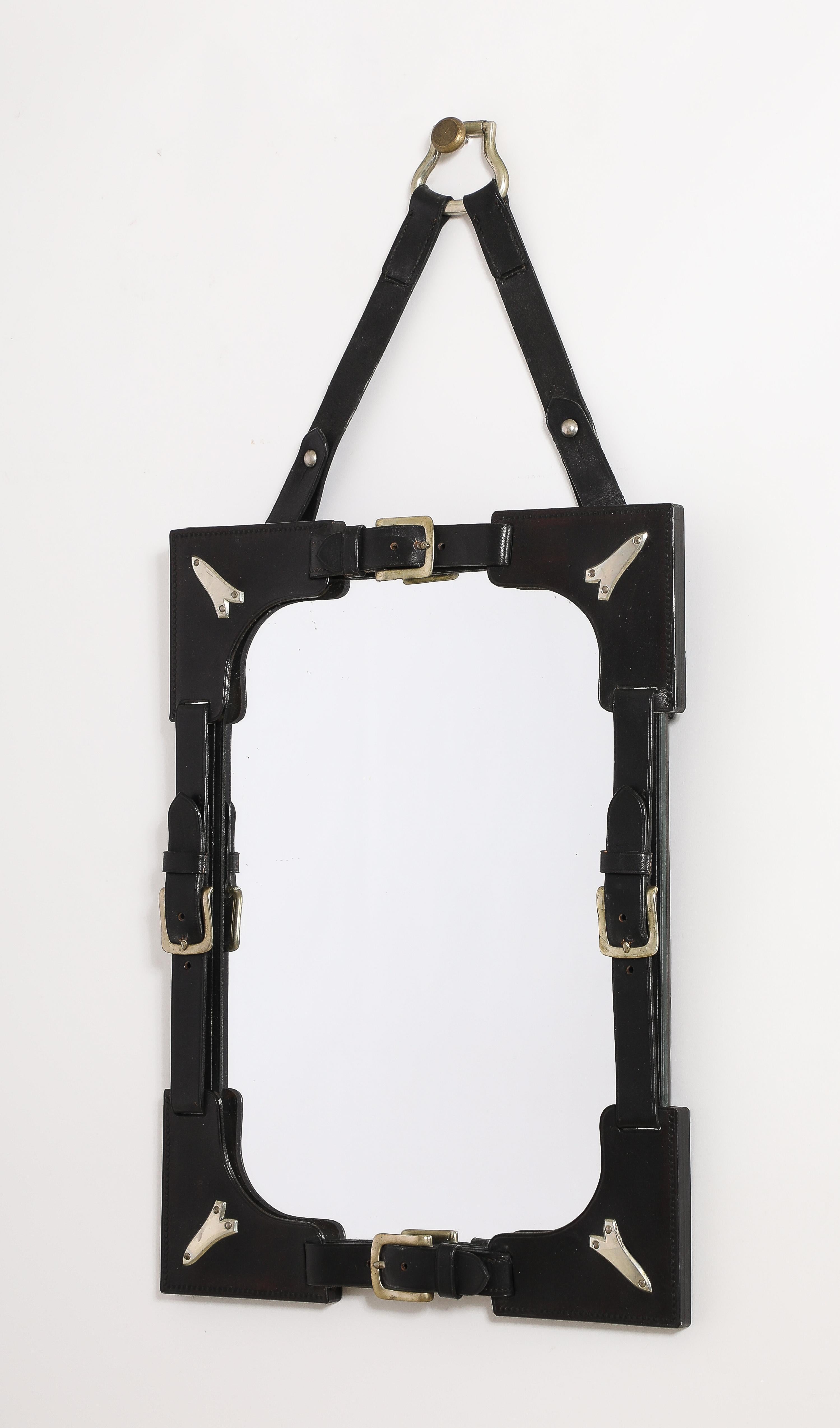 Mirror inspired by the equestrian world and in the spirit of Hermès France creations. Full leather with belt buckle details and steel and stainless steel embellishments. Large hanging strip finished with a steel ring. In good vintage condition.