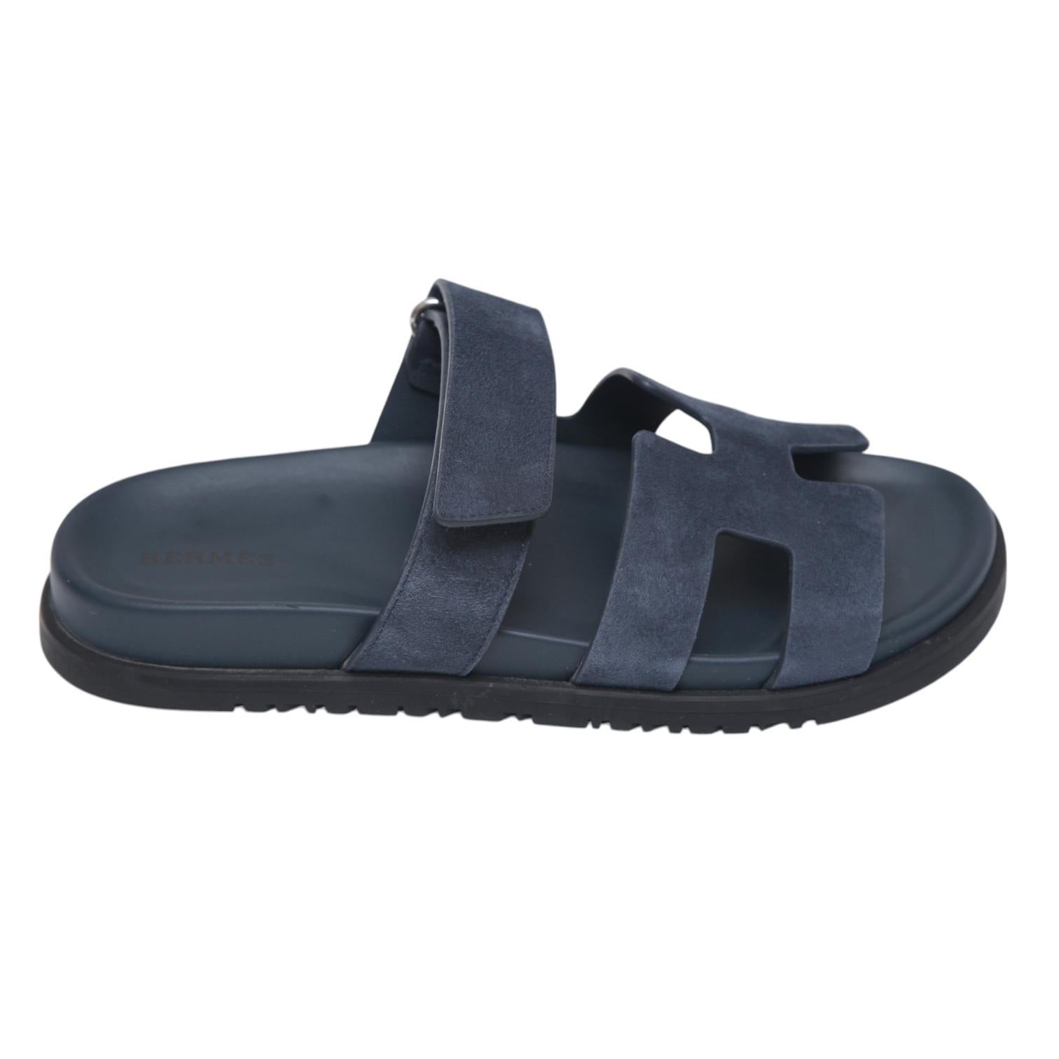GUARANTEED AUTHENTIC HERMES BLEU CELESTE SUEDE CHYPRE SANDALS

Design:
- Chypre sandals in Bleu Celeste (navy blue) suede.
- Large H strap over top of foot, adjustable.
- Leather lining.
- Rubber sole.
- Comes with dust bag.

Size: 38

Measurements